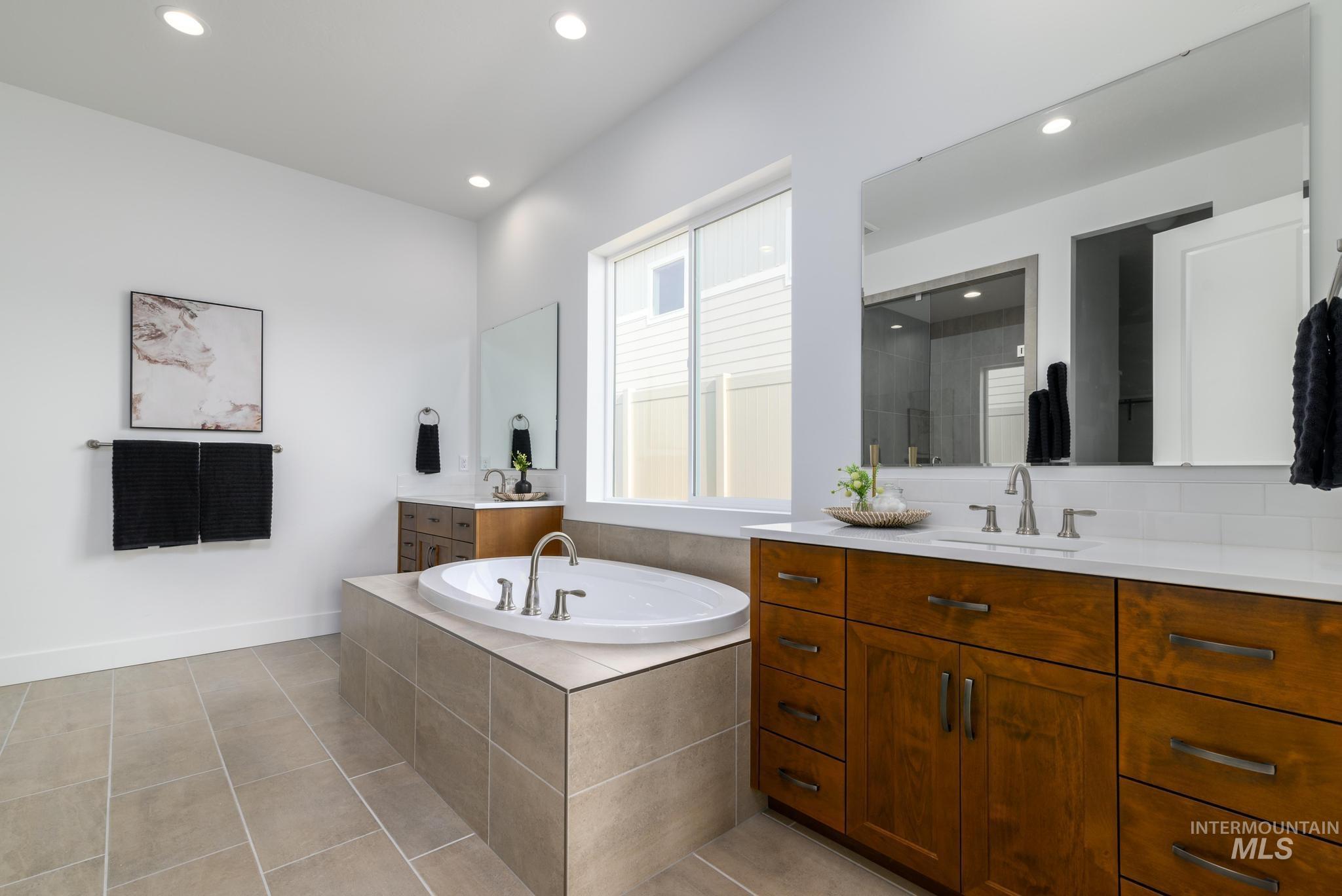 Full bath featuring two vanities, a garden tub, recessed lighting, light tile patterned floors, and a shower stall