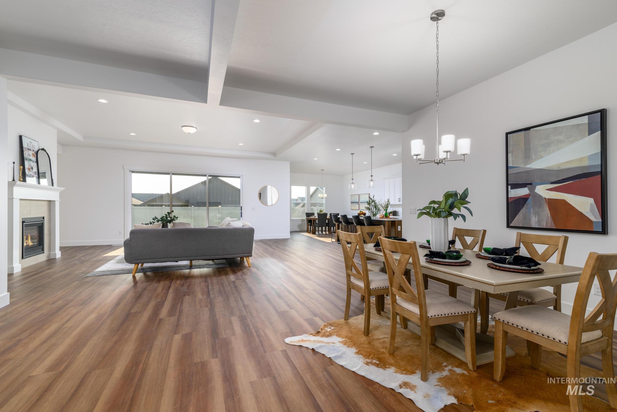 Dining room with beam ceiling, wood finished floors, a glass covered fireplace, a chandelier, and recessed lighting