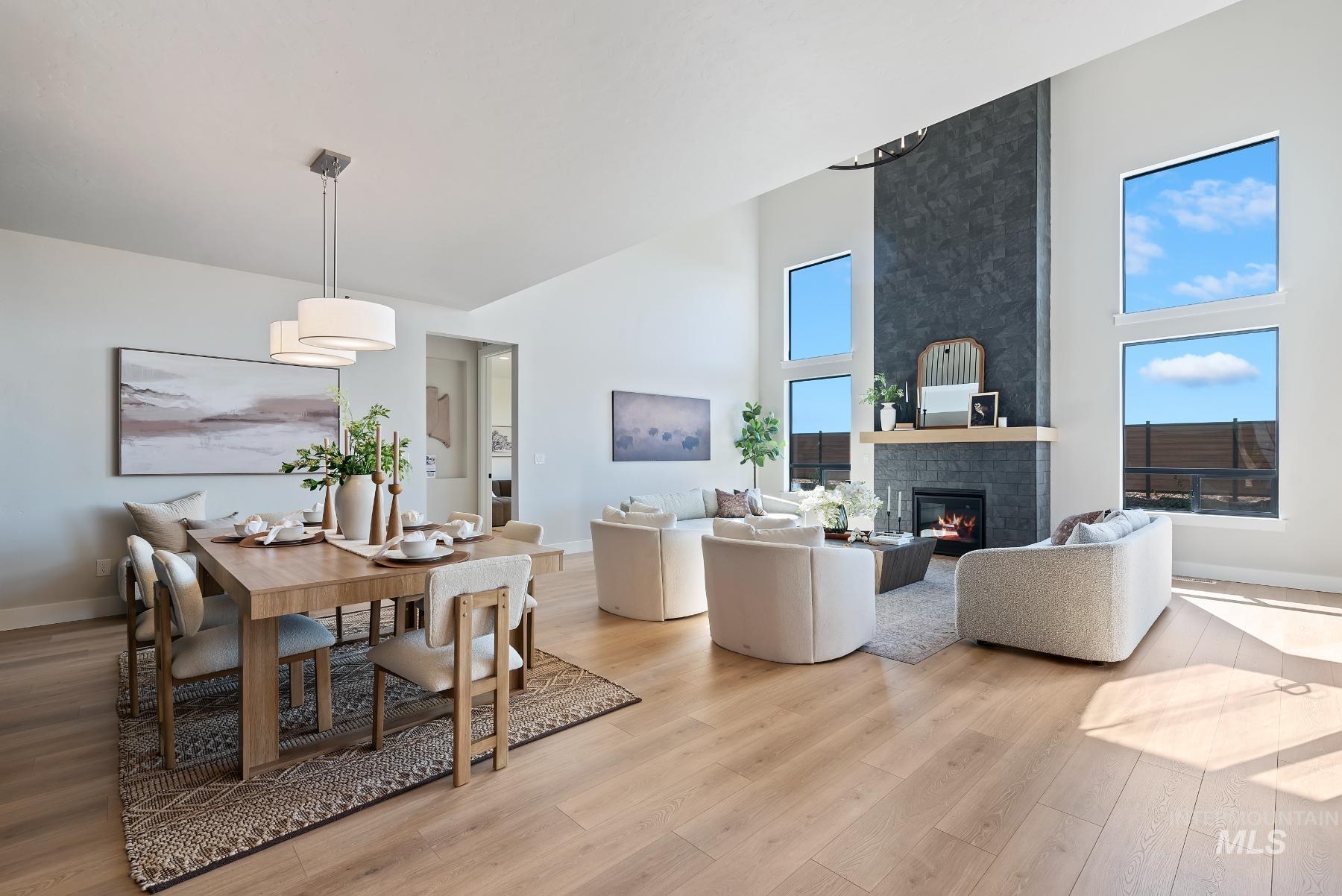 Dining space featuring light wood-style flooring, a fireplace, and a towering ceiling