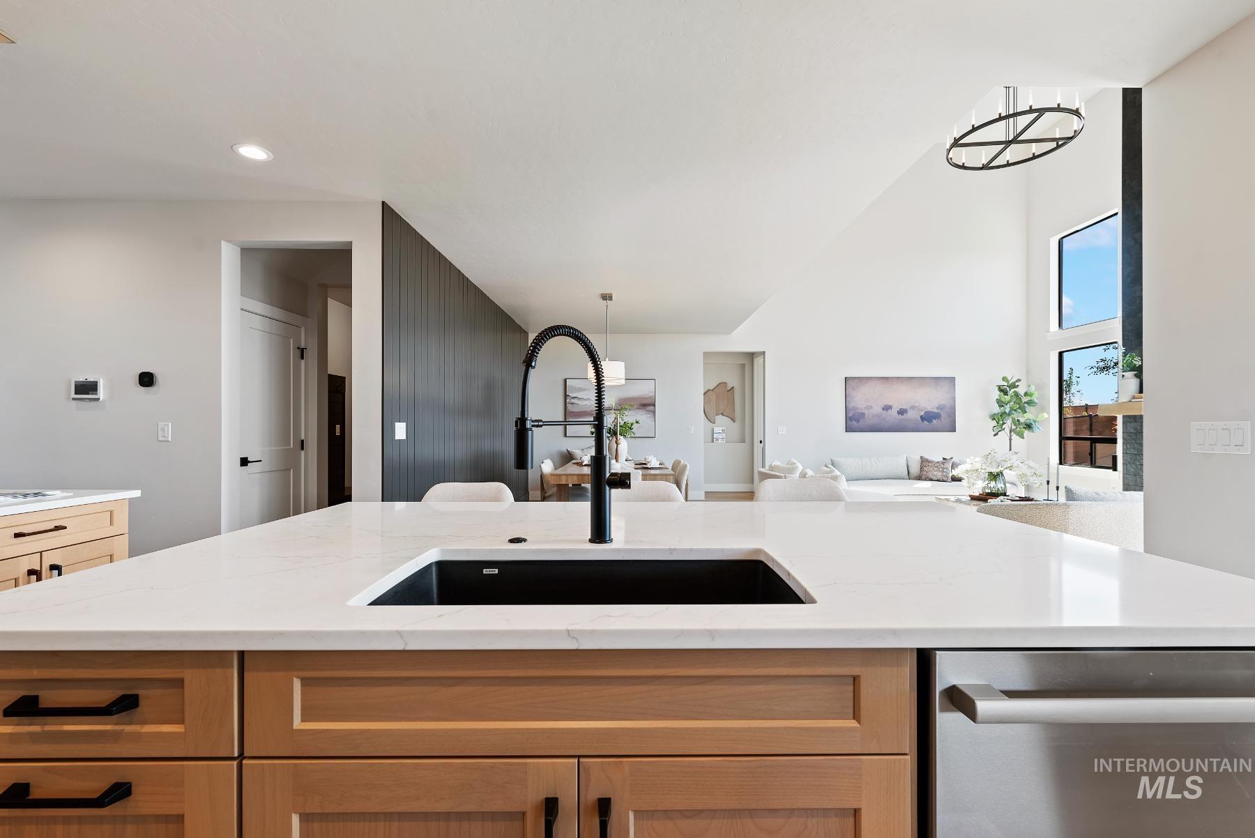 Kitchen featuring dishwasher, light brown cabinets, light stone countertops, and a chandelier