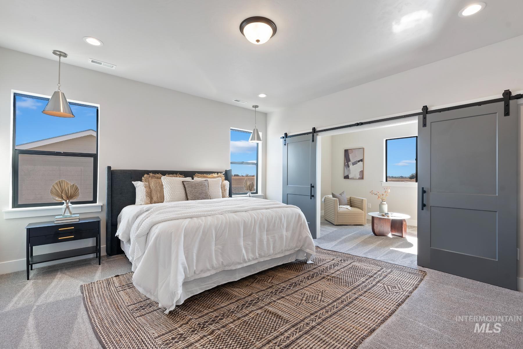 Bedroom with carpet flooring, recessed lighting, multiple windows, and a barn door