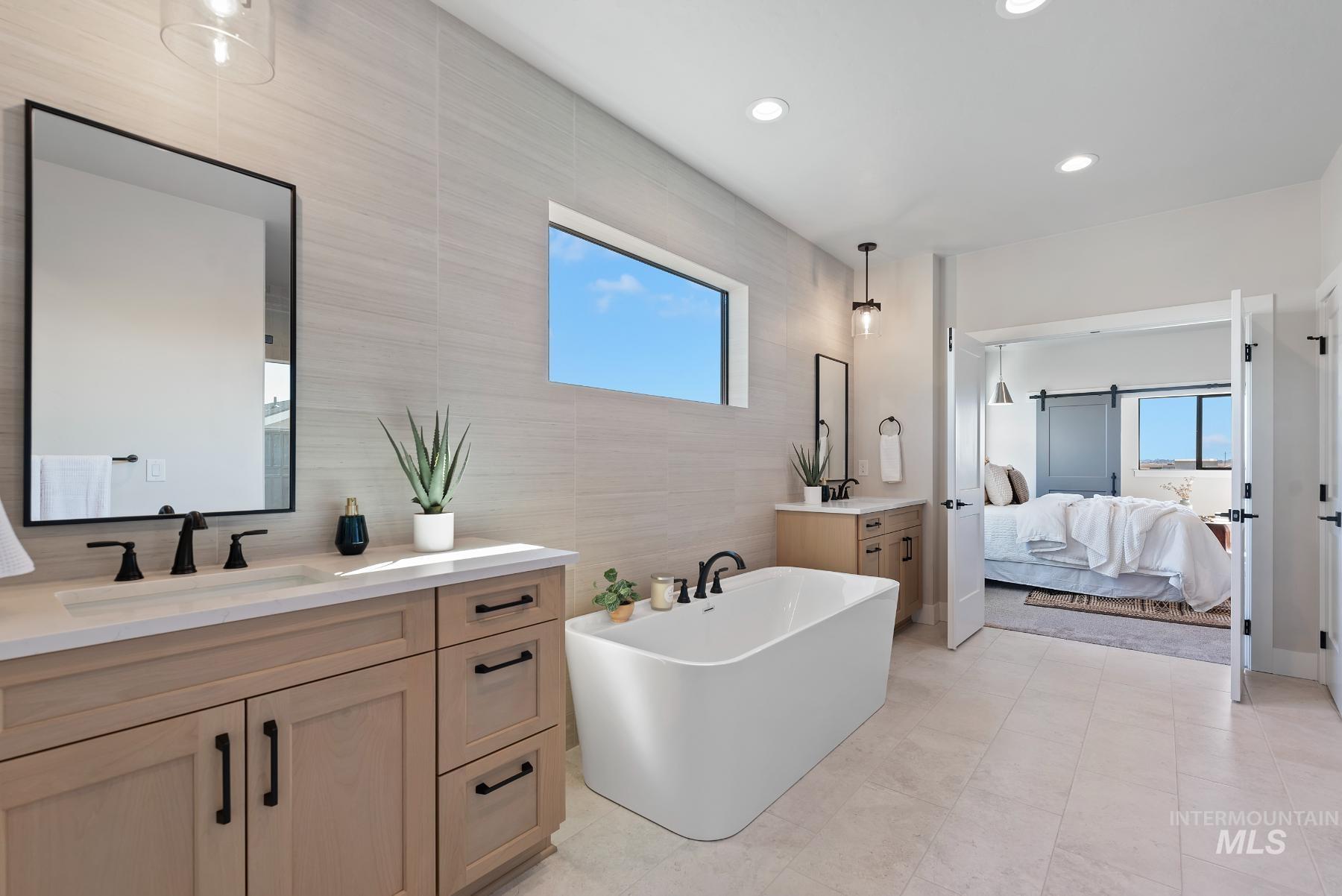 Ensuite bathroom with tile walls, two vanities, a soaking tub, recessed lighting, and light tile patterned flooring
