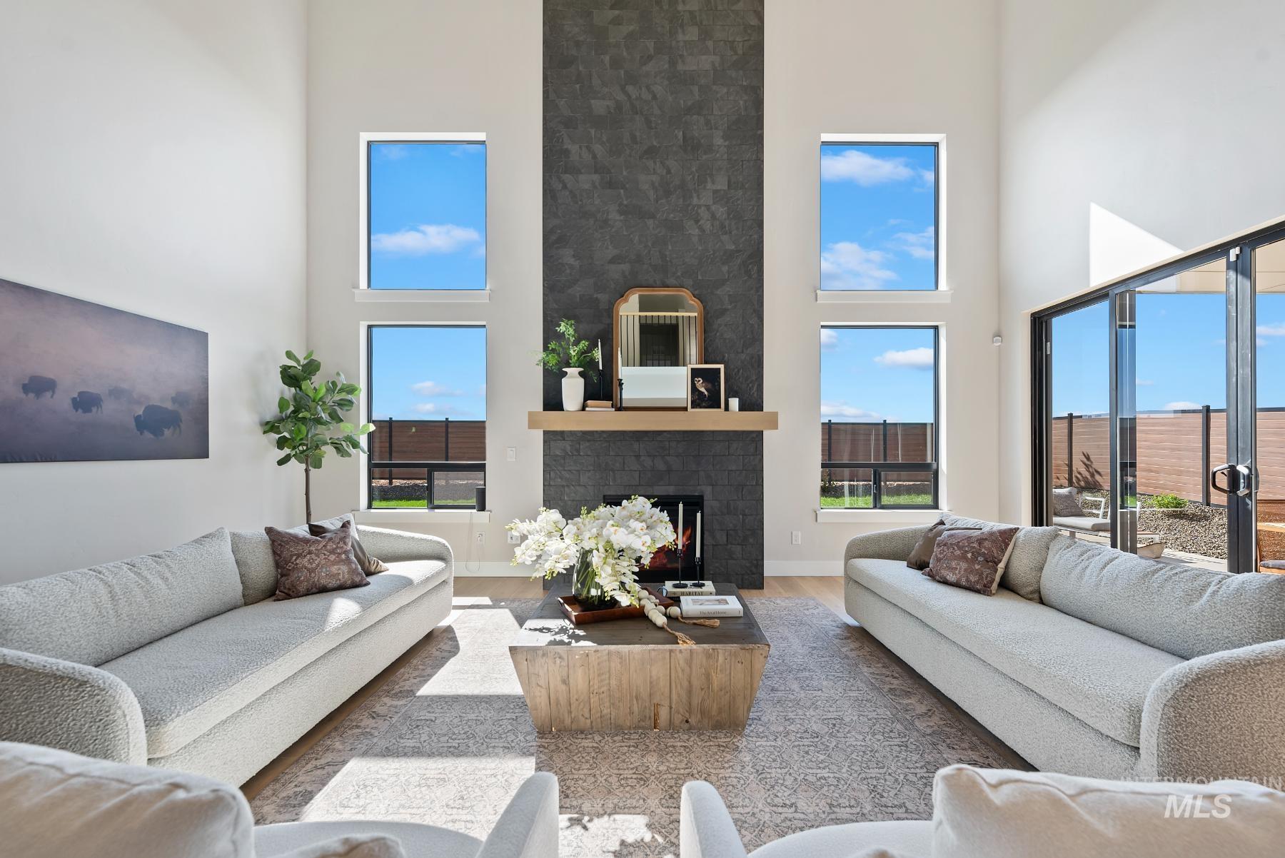 Living room featuring a brick fireplace, wood finished floors, and a high ceiling