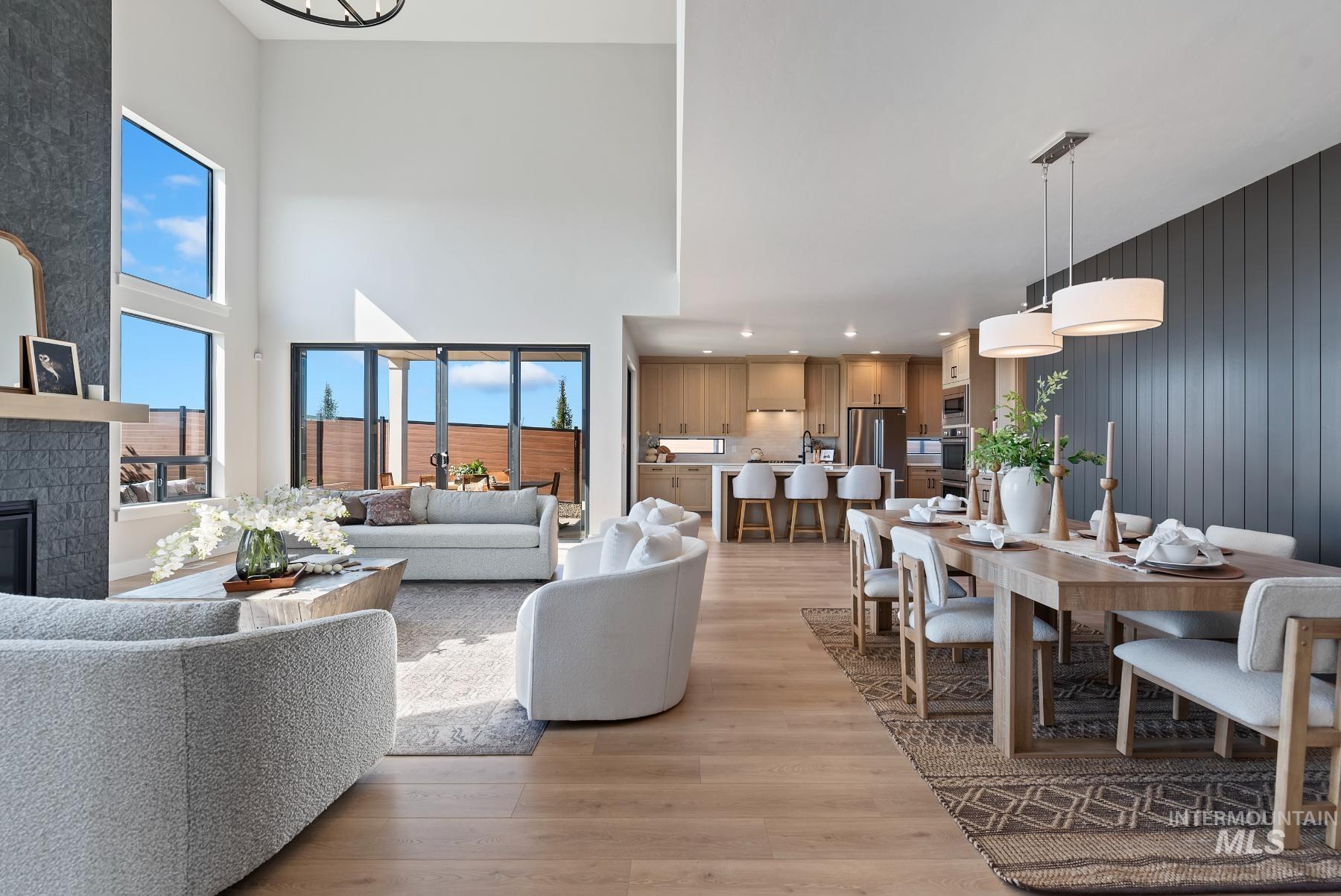 Living area featuring light wood-type flooring, a large fireplace, and a towering ceiling