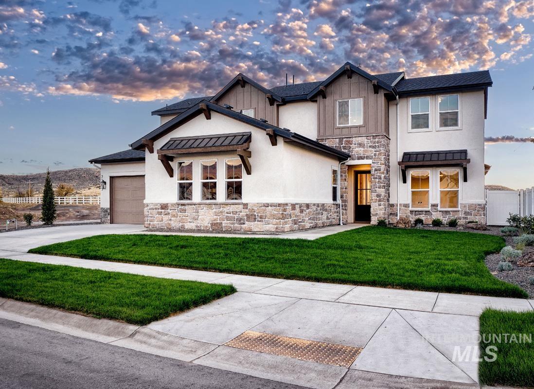 View of front facade with stone siding, a standing seam roof, a metal roof, concrete driveway, and an attached garage