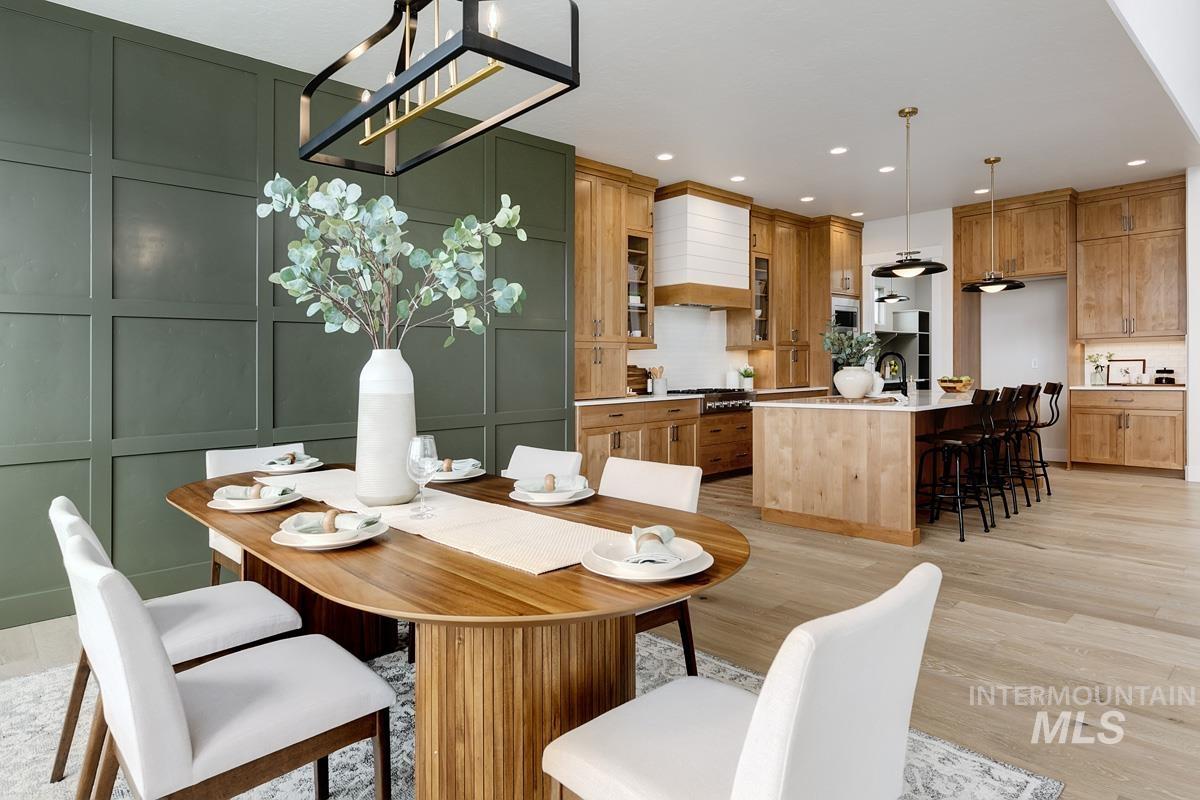 Dining space with a decorative wall, light wood-type flooring, recessed lighting, and a chandelier