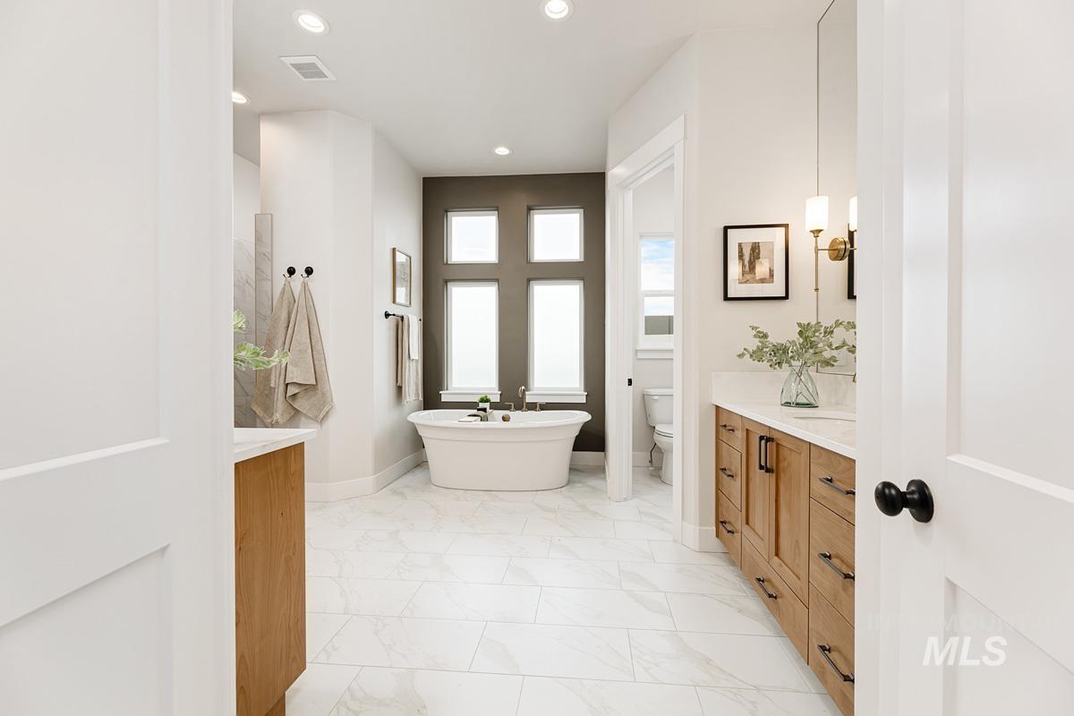 Full bathroom with vanity, a freestanding bath, light marble finish flooring, and recessed lighting