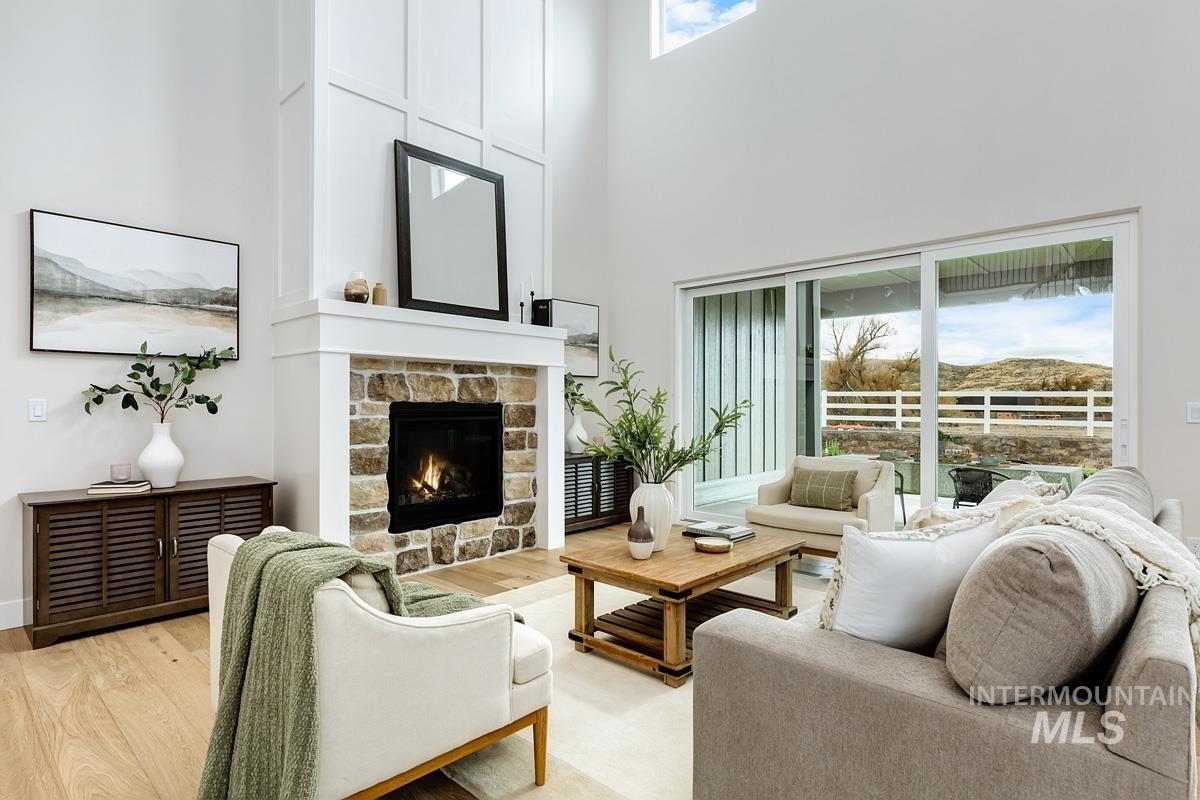 Living area with light wood-style floors, a towering ceiling, and a stone fireplace