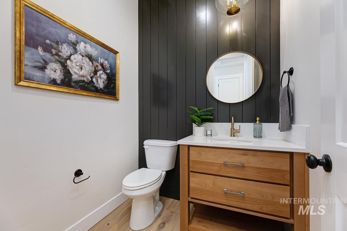 Half bath featuring vanity, light wood finished floors, and wood walls
