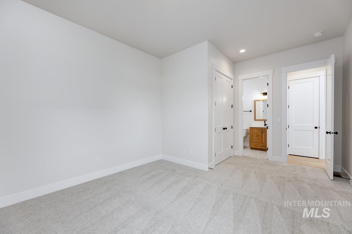 Unfurnished bedroom featuring light colored carpet, a closet, recessed lighting, and connected bathroom