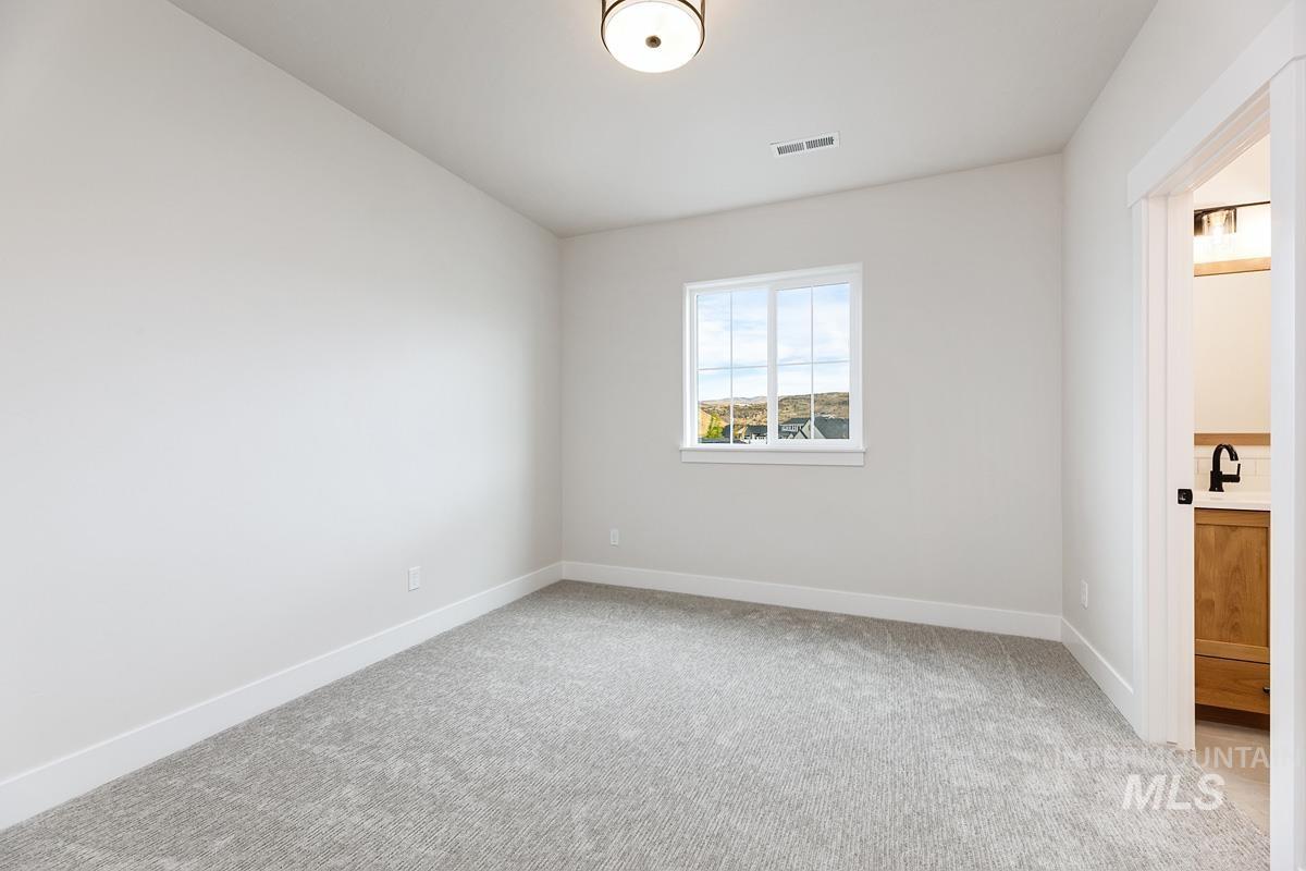 Unfurnished bedroom with light colored carpet and connected bathroom