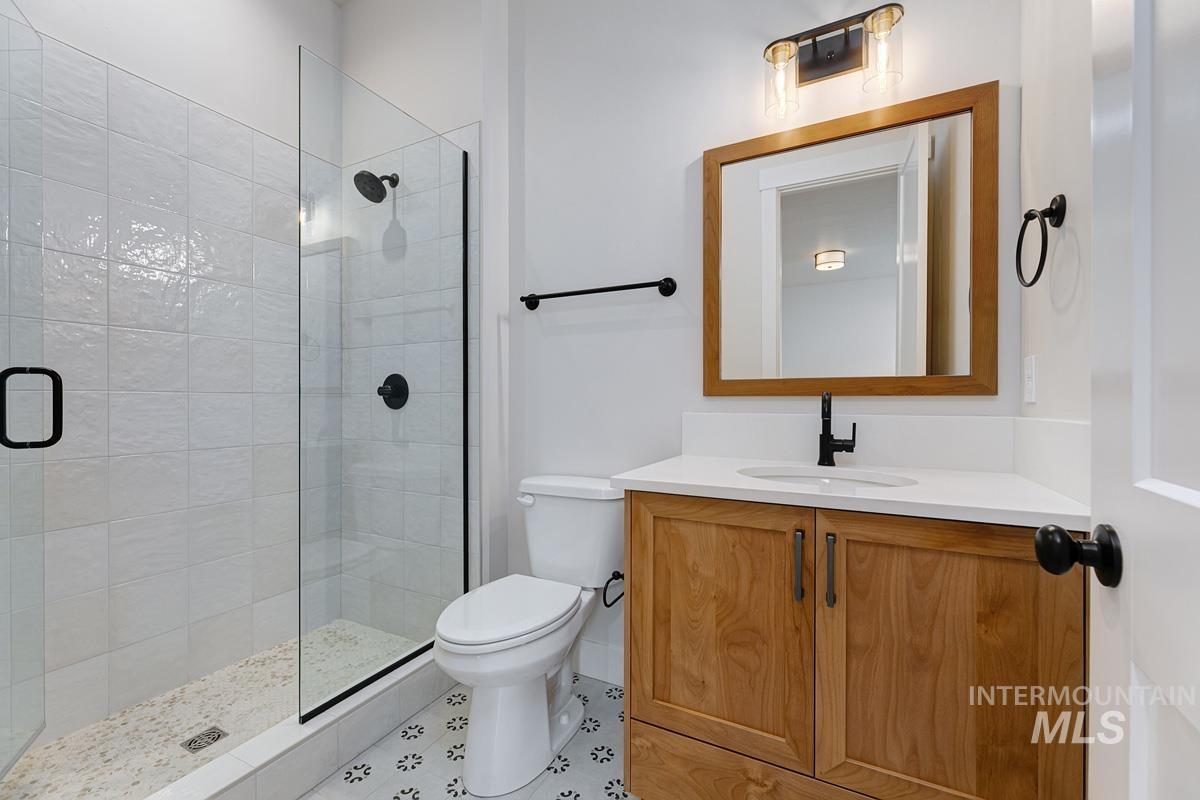 Bathroom featuring a shower stall, vanity, and tile patterned flooring