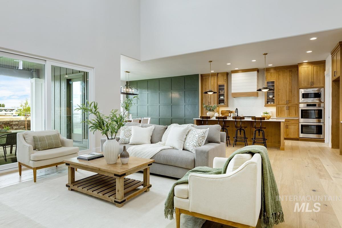 Living room featuring light wood-style floors, recessed lighting, and a high ceiling