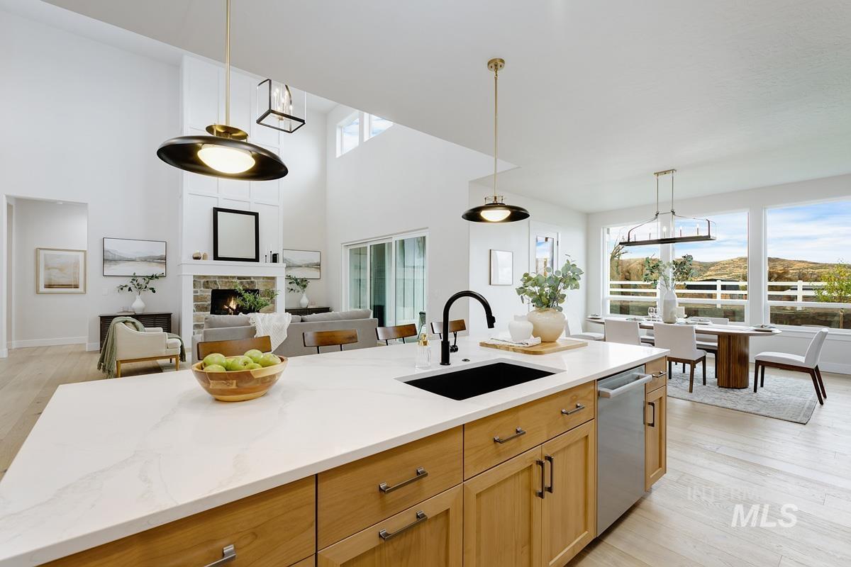 Kitchen featuring light wood-style floors, pendant lighting, a fireplace, open floor plan, and dishwasher
