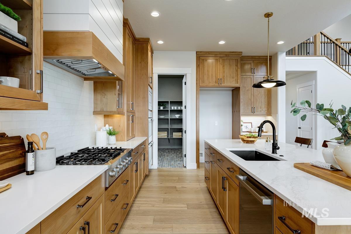Kitchen featuring recessed lighting, brown cabinets, appliances with stainless steel finishes, light wood-style floors, and pendant lighting