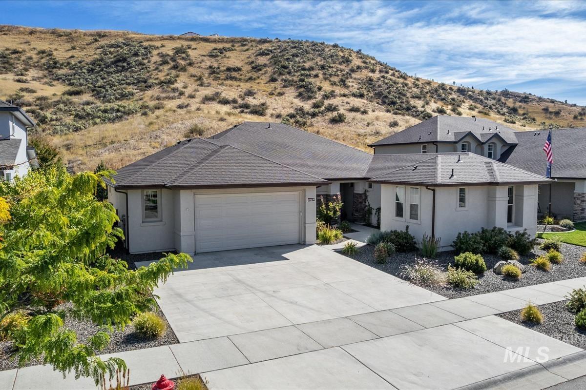 View of front of property featuring stucco siding, driveway, an attached garage, roof with shingles, and a mountain view