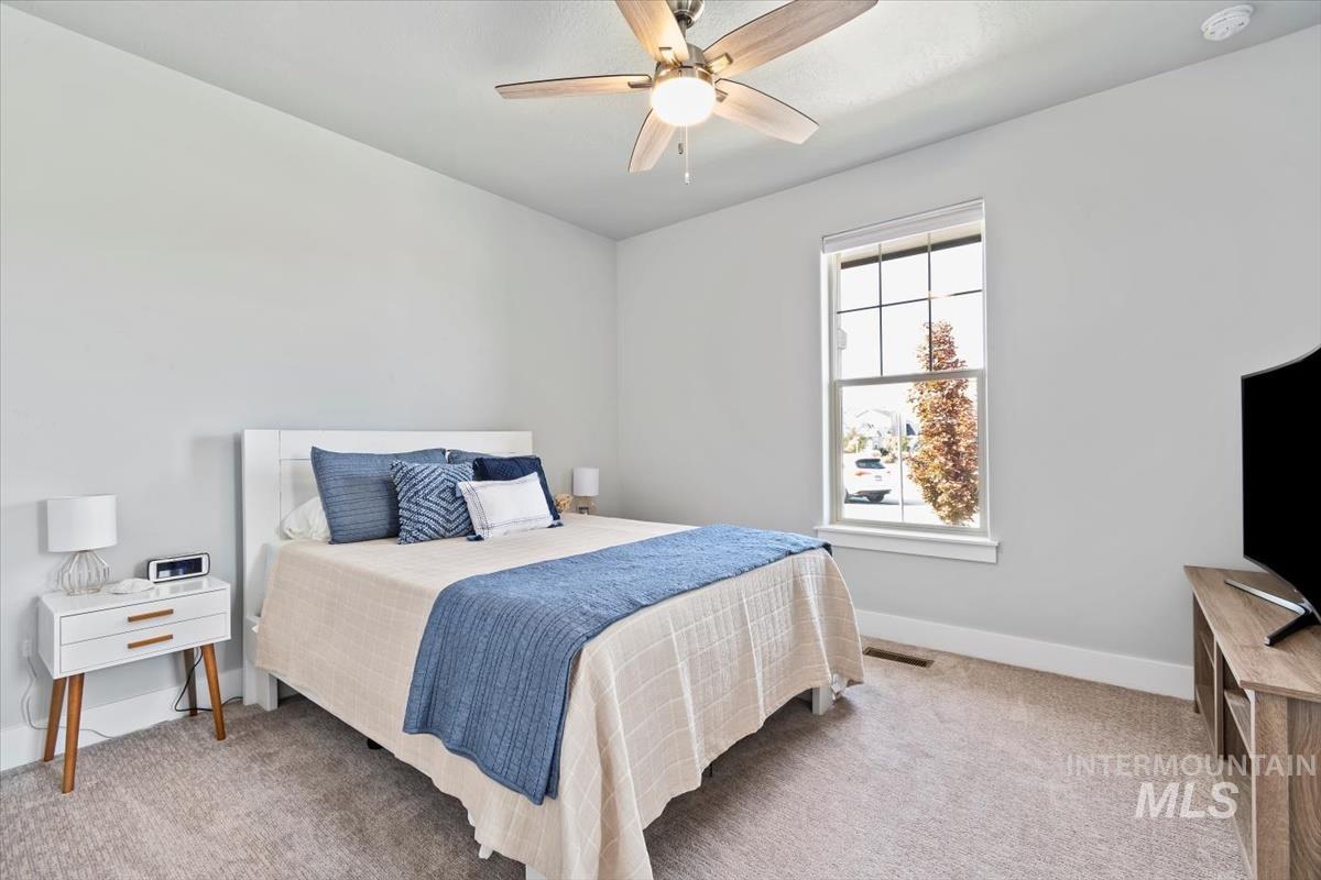 Bedroom with light carpet and a ceiling fan