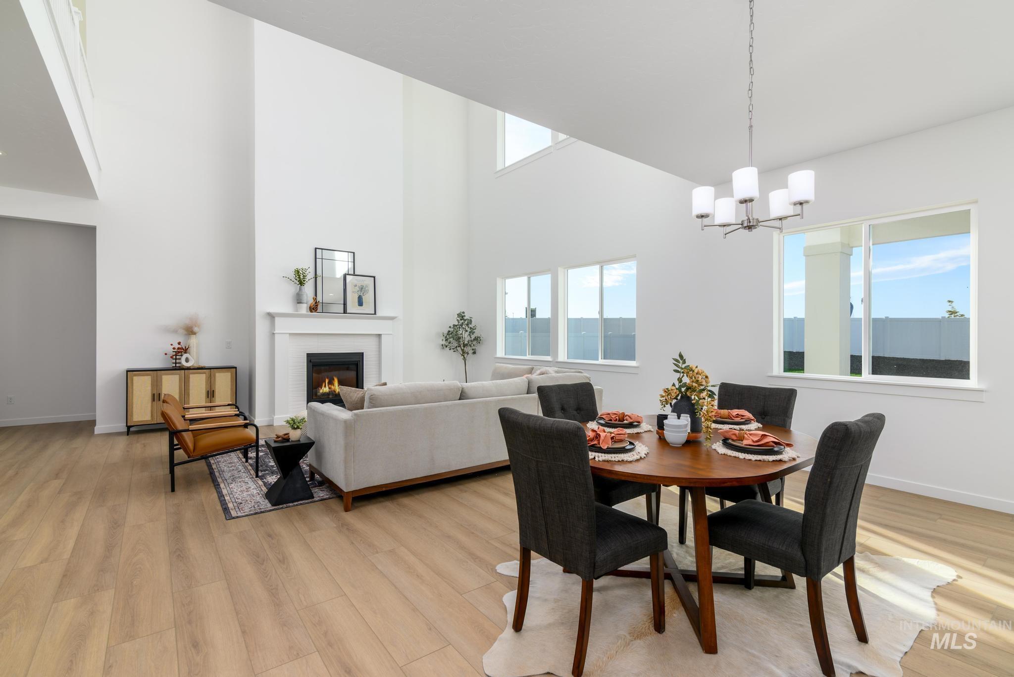Dining room with light wood-style floors, a brick fireplace, a chandelier, and a towering ceiling