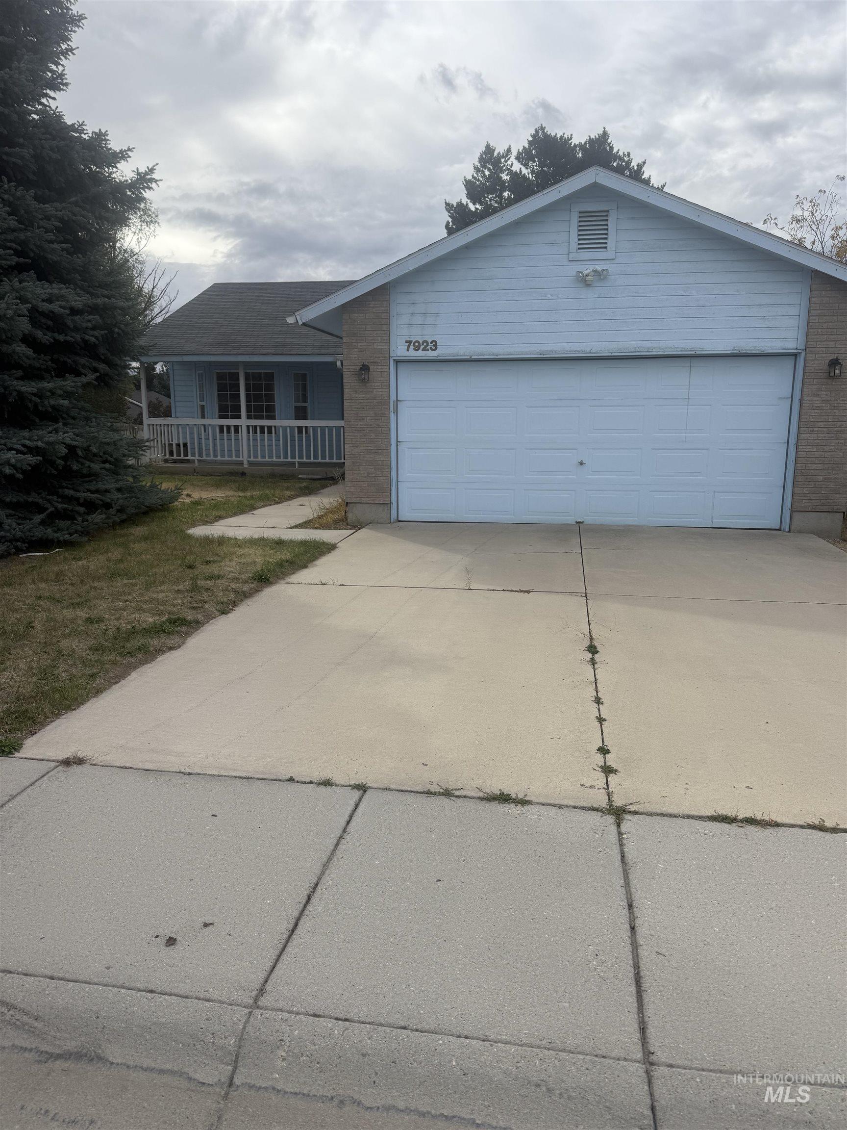 Single story home with concrete driveway, a porch, and brick siding
