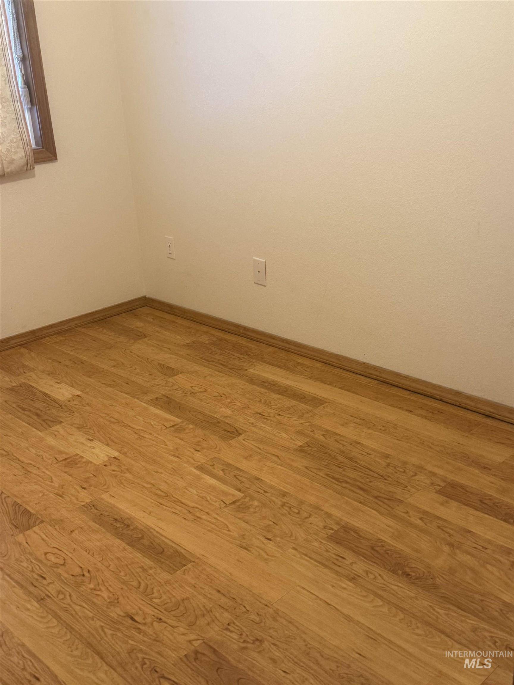 Empty room with baseboards and light wood-style floors