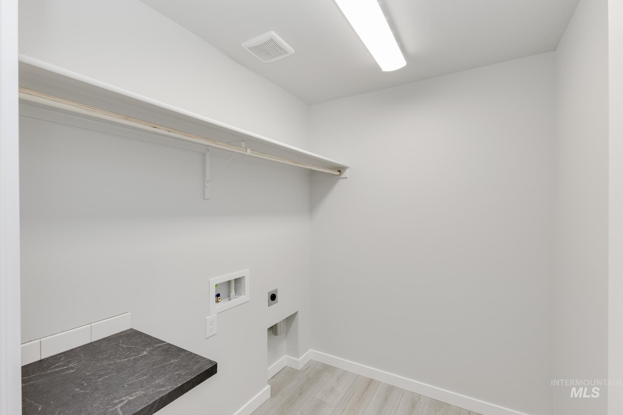 Laundry area with light wood-style floors, washer hookup, and hookup for an electric dryer