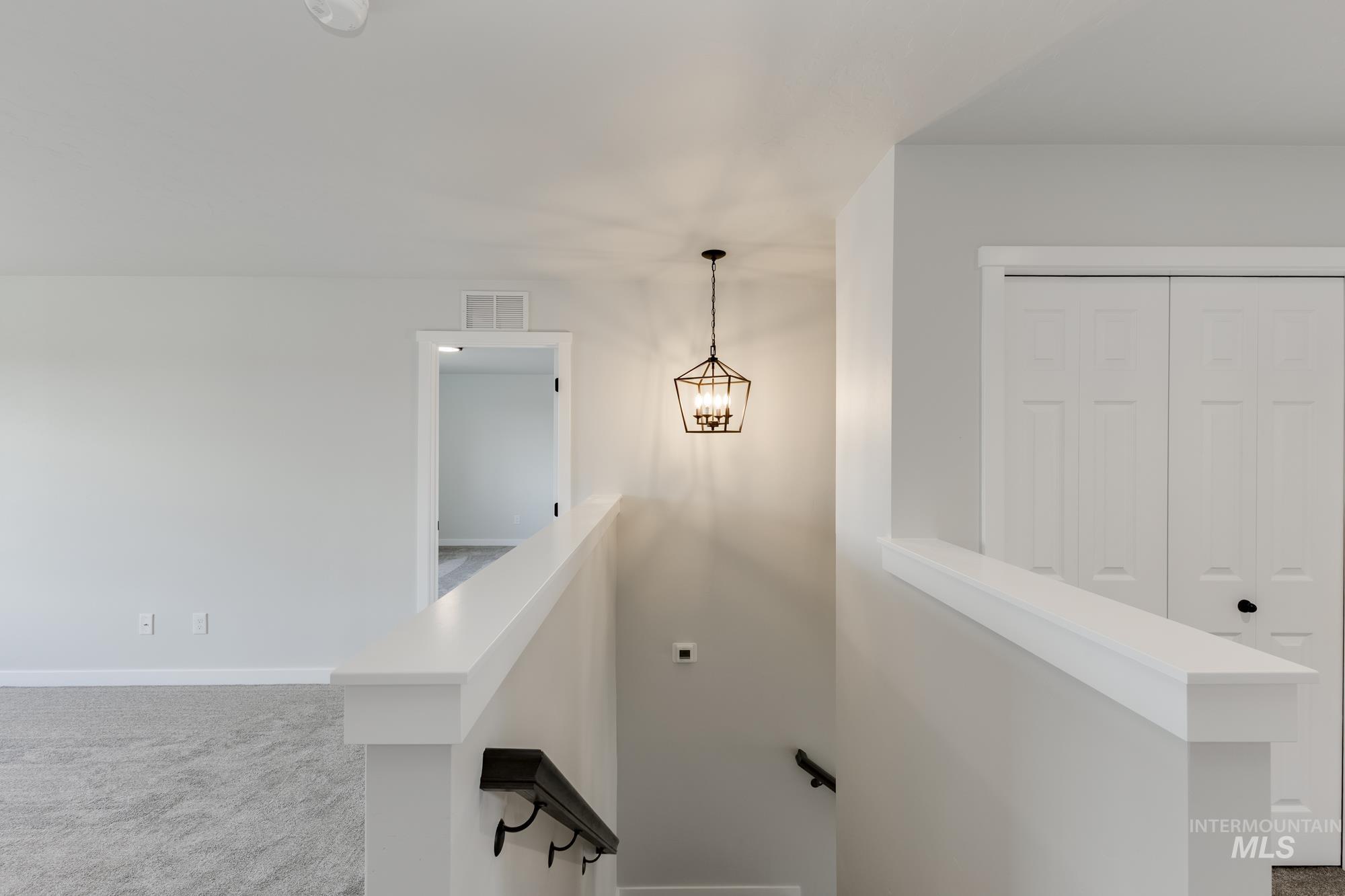 Stairs with carpet floors and a chandelier
