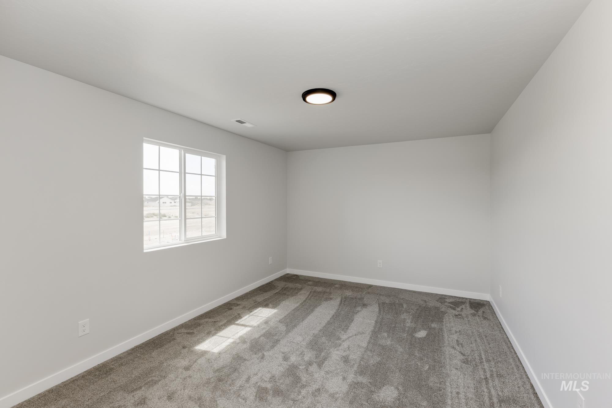Carpeted spare room featuring baseboards