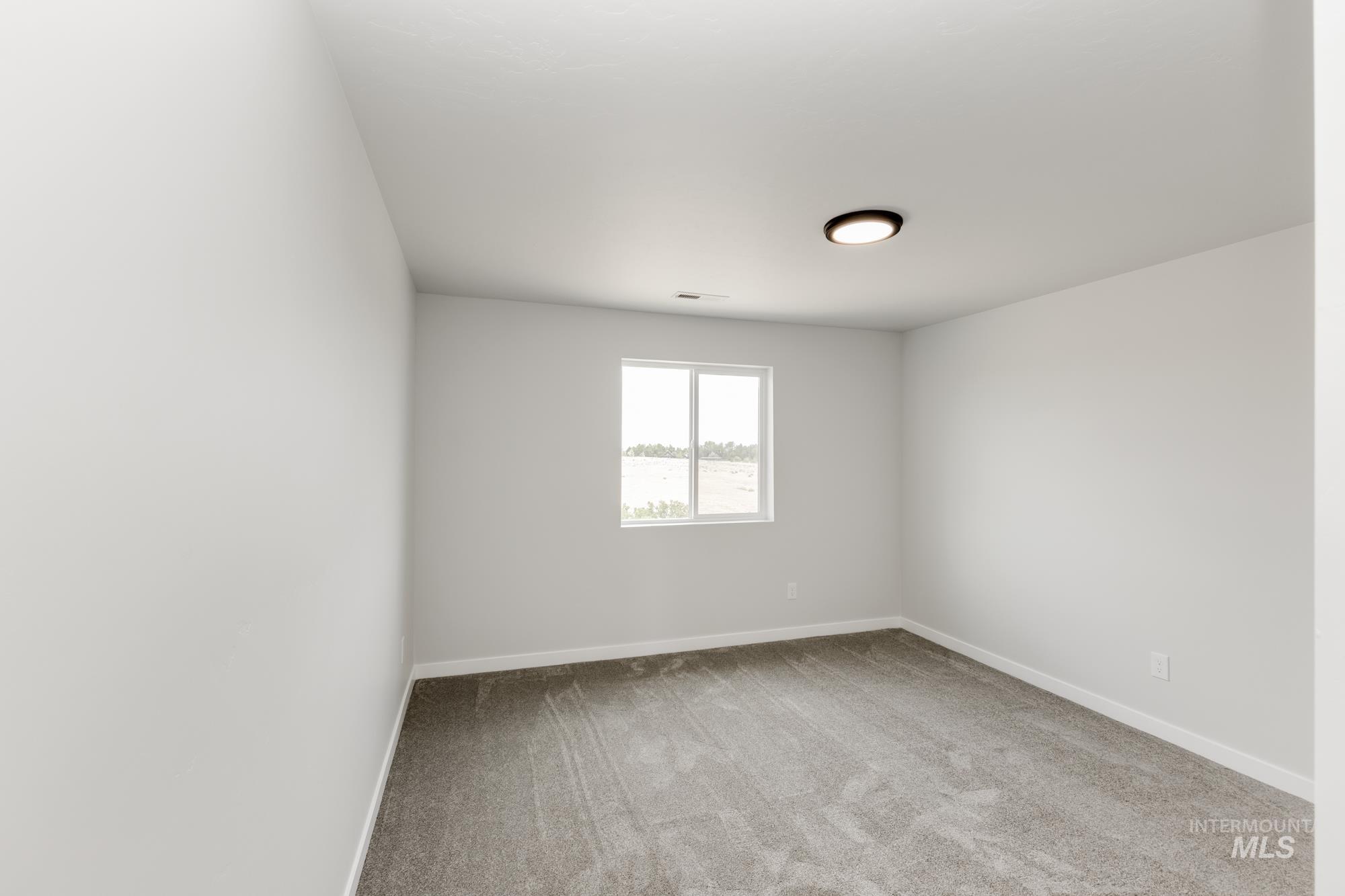 Spare room featuring light carpet and baseboards