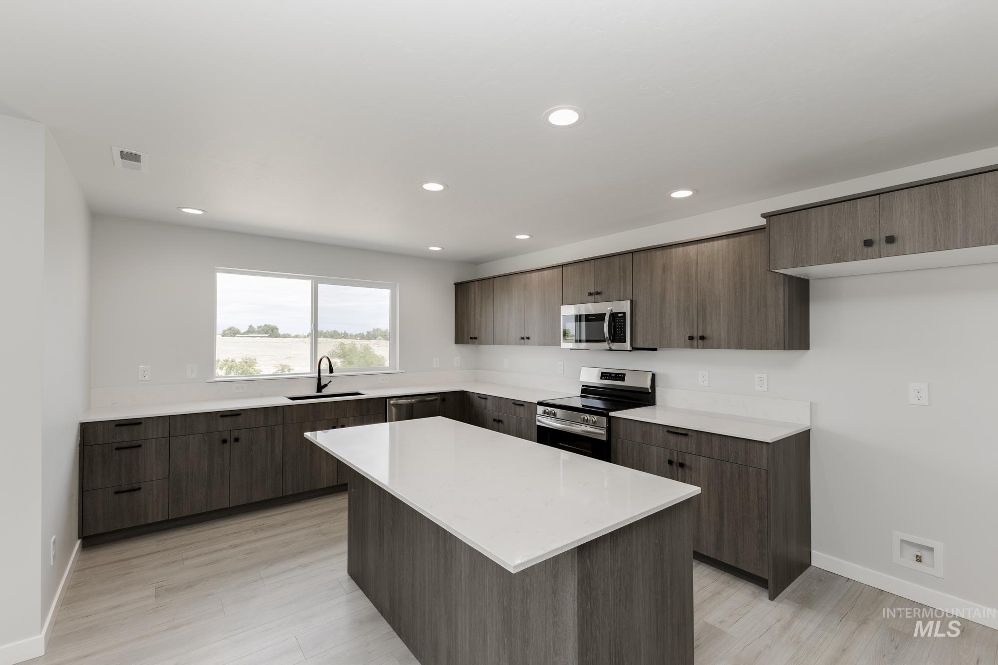 Kitchen with stainless steel appliances, a kitchen island, recessed lighting, modern cabinets, and light wood-style floors