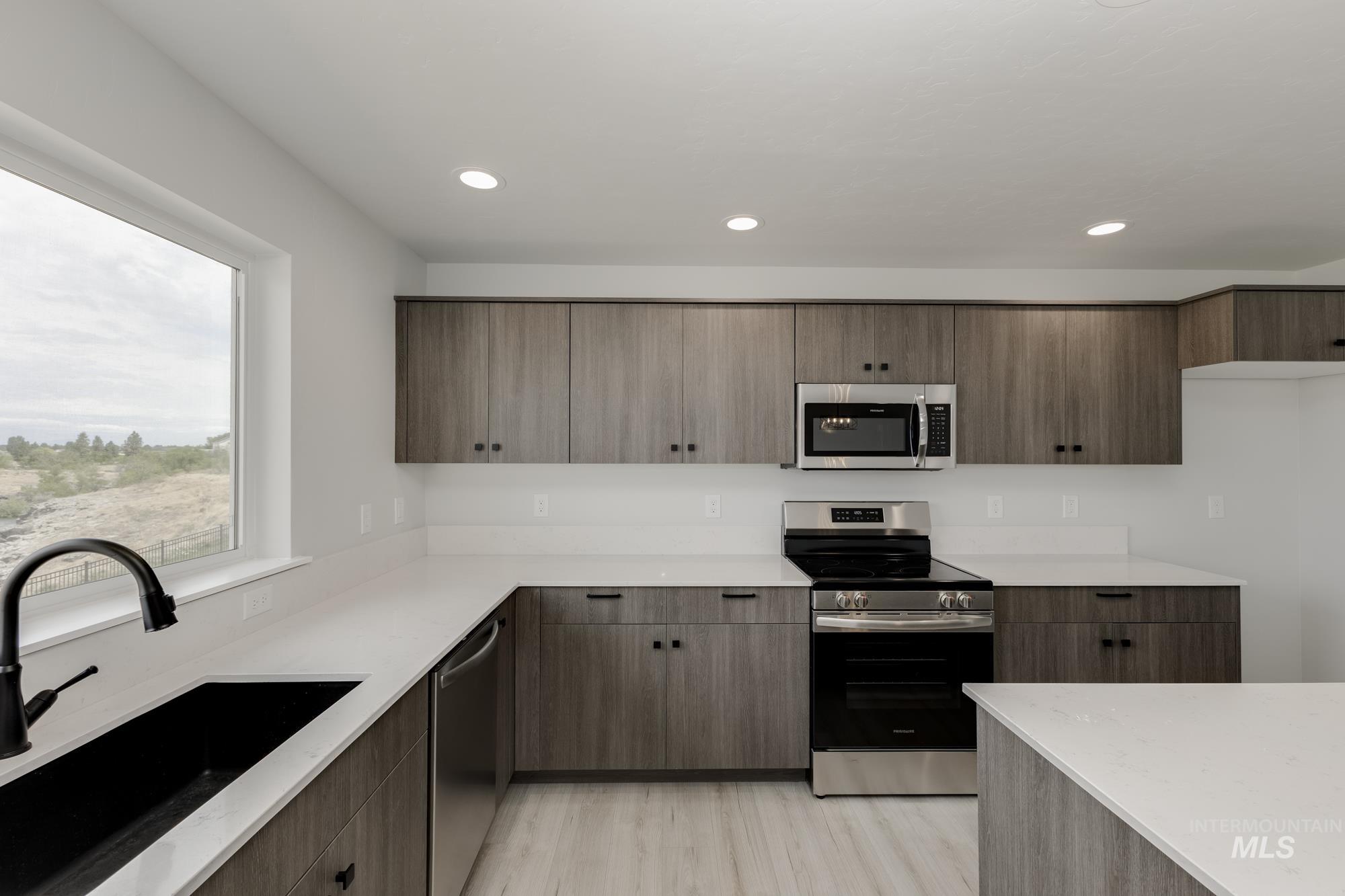 Kitchen featuring appliances with stainless steel finishes, modern cabinets, recessed lighting, light wood-style floors, and light stone counters