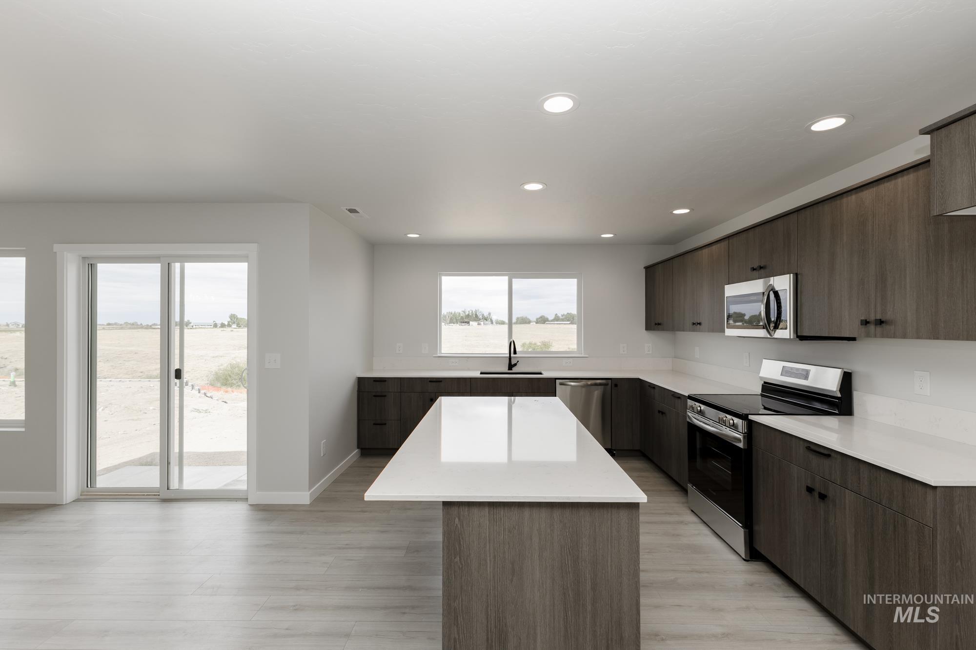 Kitchen featuring modern cabinets, stainless steel appliances, a kitchen island, light wood finished floors, and recessed lighting
