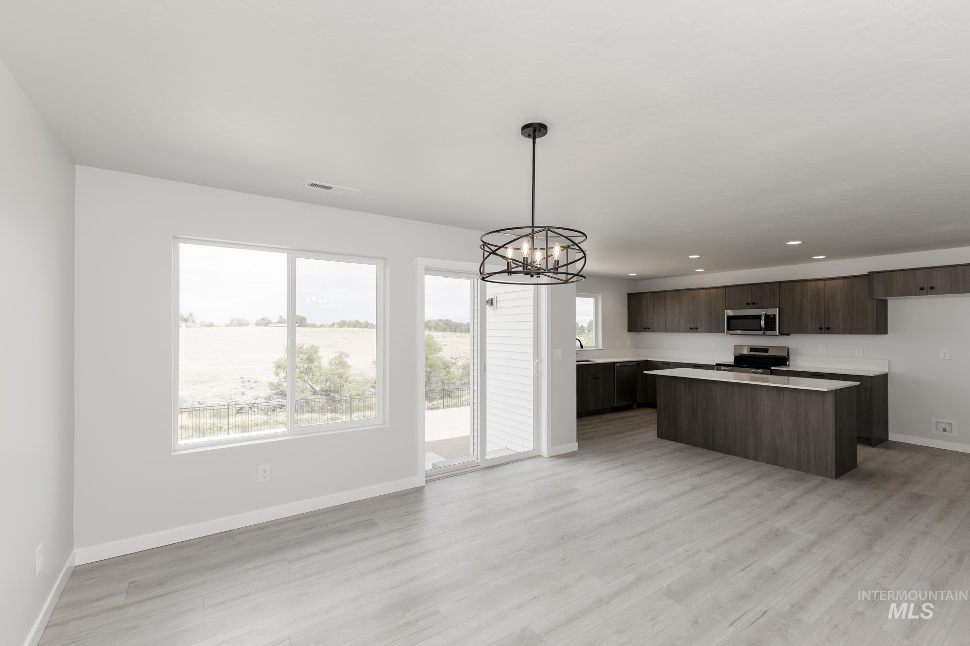 Kitchen featuring light countertops, a chandelier, hanging light fixtures, light wood finished floors, and a center island