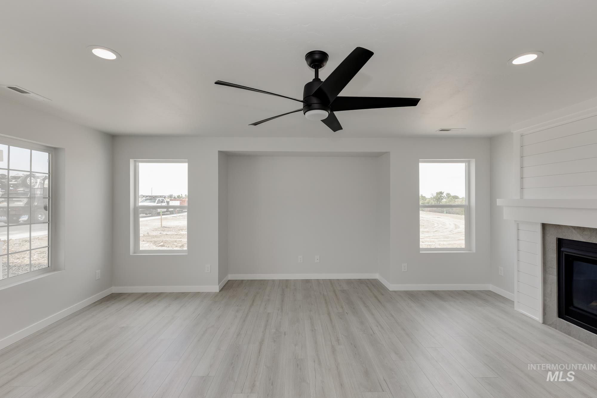 Unfurnished living room with light wood-type flooring, recessed lighting, a glass covered fireplace, and a ceiling fan