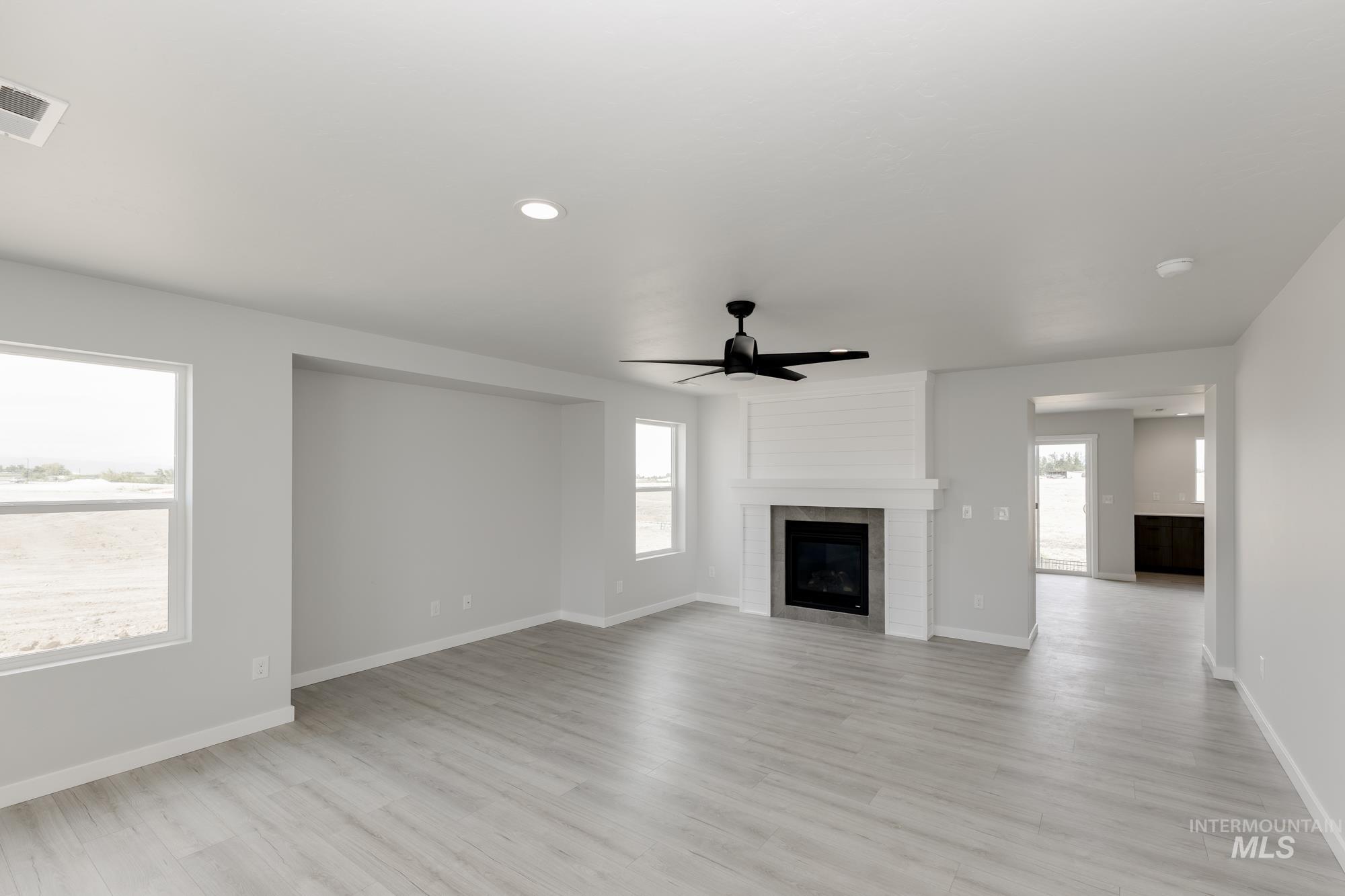 Unfurnished living room featuring light wood-type flooring, a ceiling fan, a fireplace, and recessed lighting