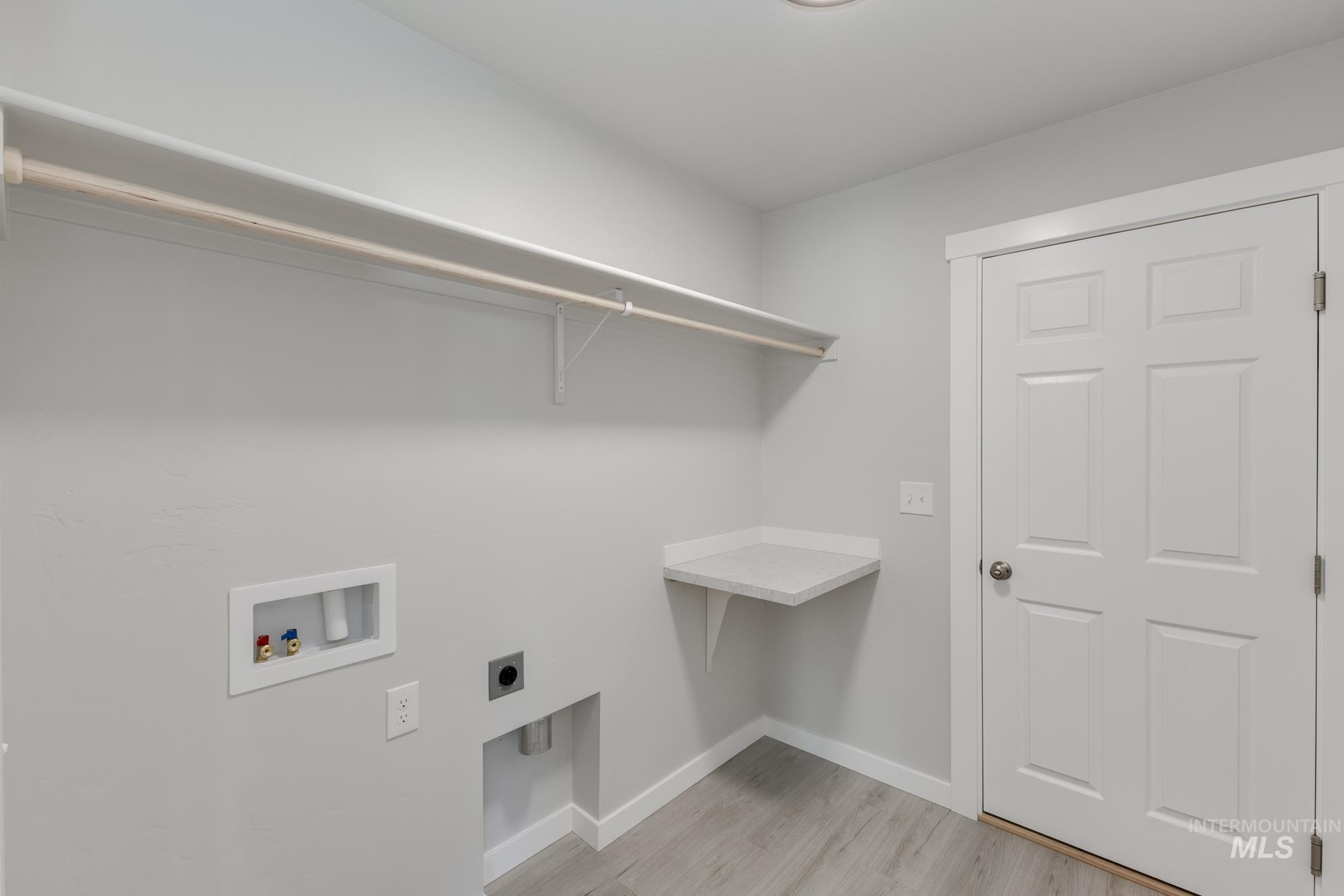 Washroom with light wood-style floors, washer hookup, and hookup for an electric dryer