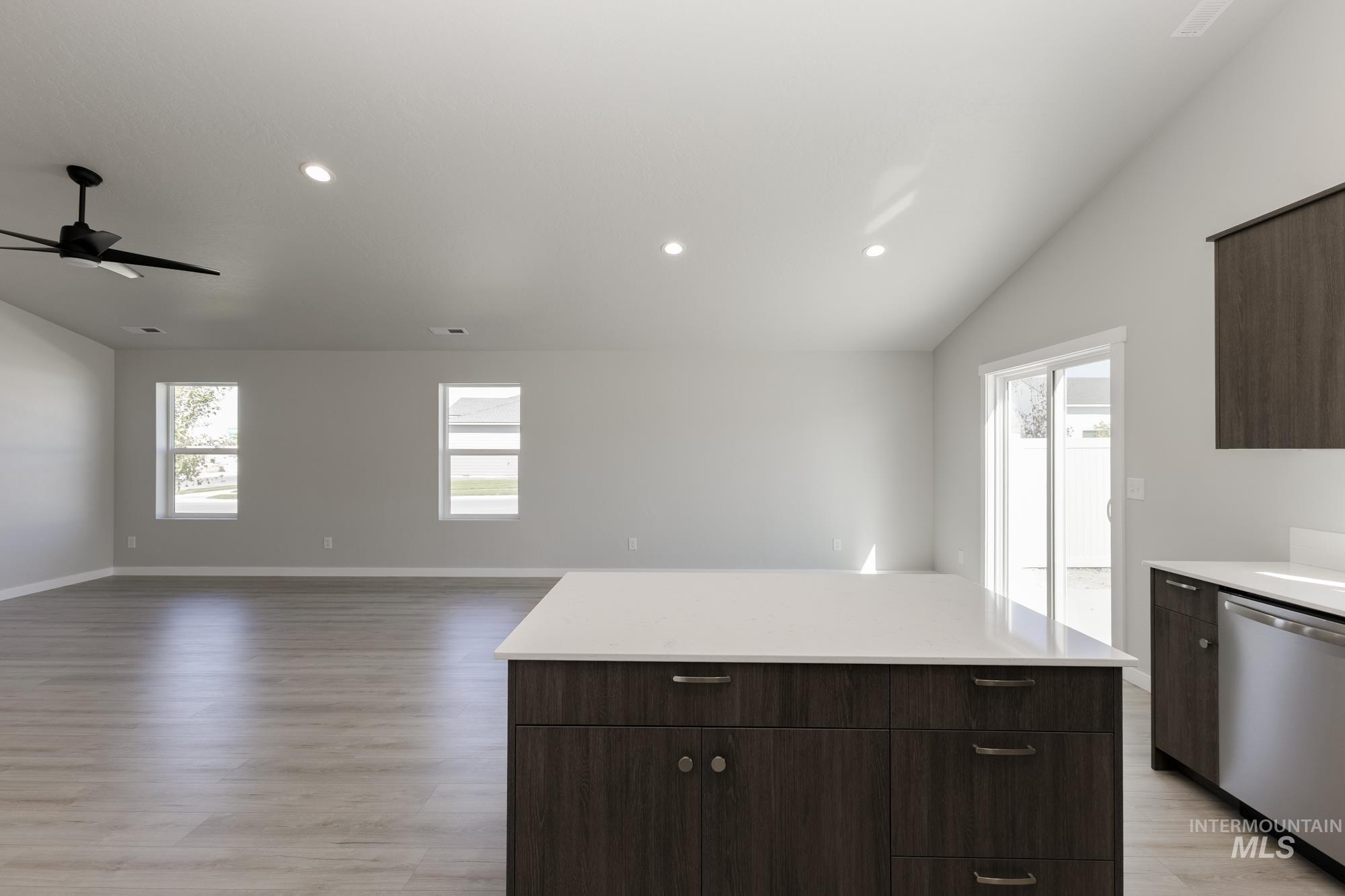 Kitchen with dark brown cabinetry, vaulted ceiling, a center island, dishwasher, and plenty of natural light