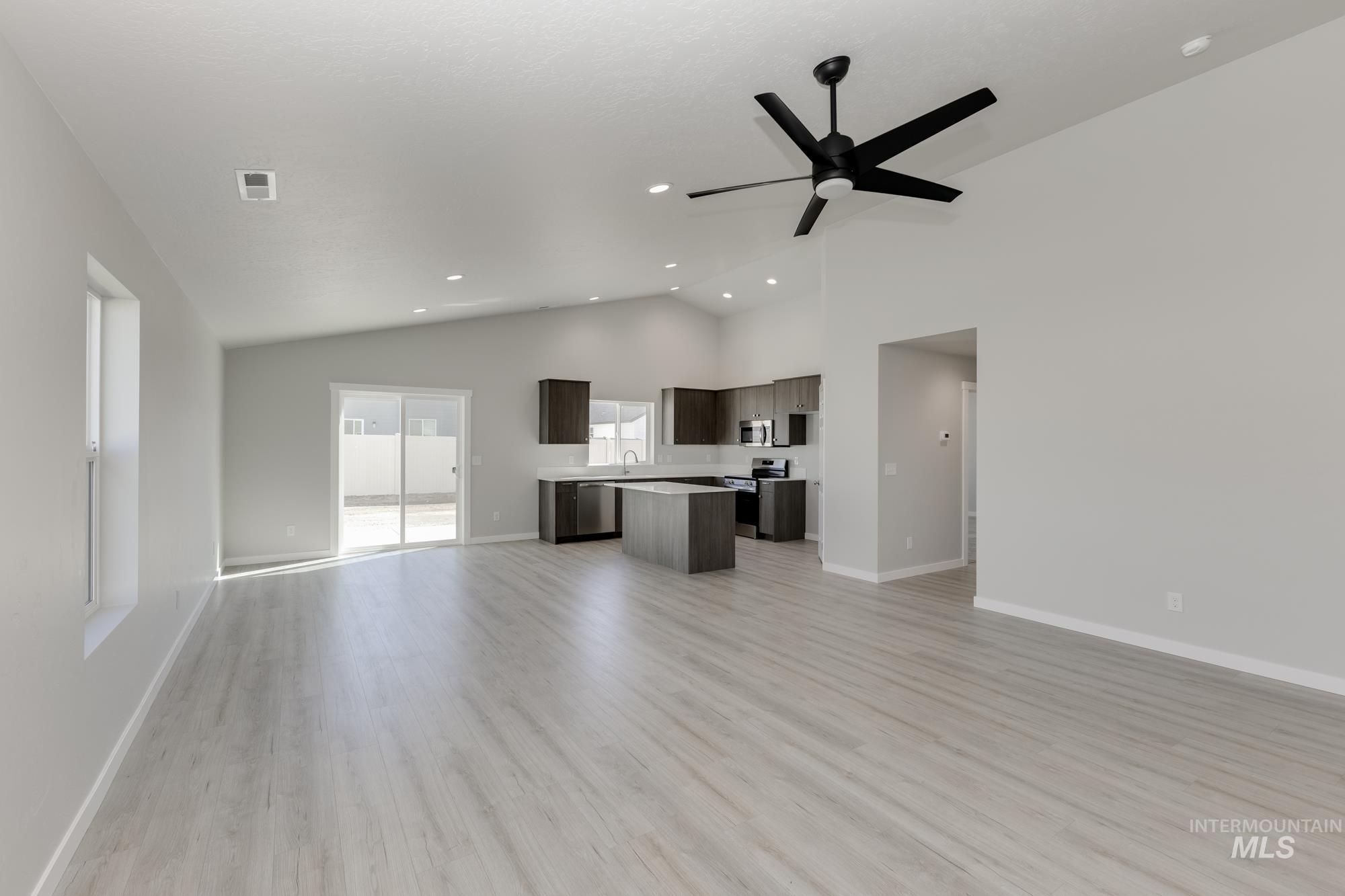 Unfurnished living room featuring light wood finished floors, high vaulted ceiling, a ceiling fan, and recessed lighting
