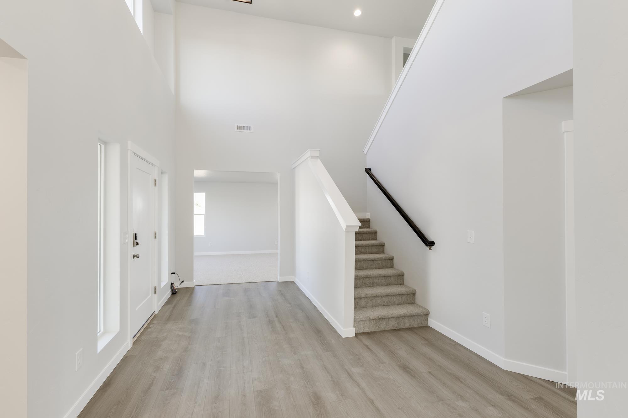 Foyer entrance featuring stairs, light wood-style floors, a towering ceiling, and recessed lighting
