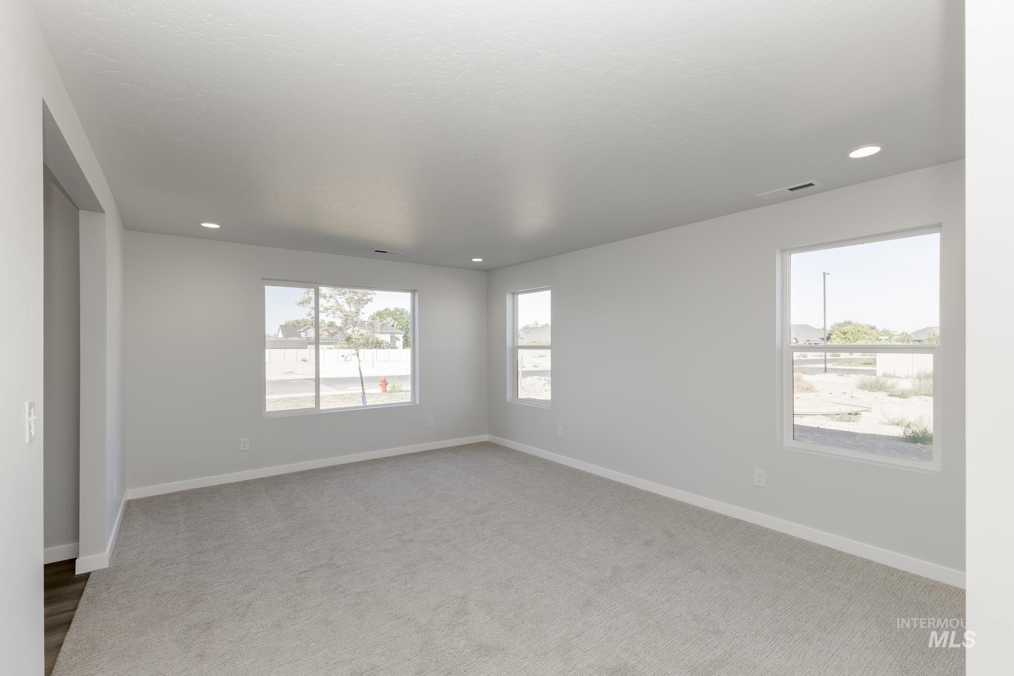 Empty room with carpet floors, healthy amount of natural light, and recessed lighting