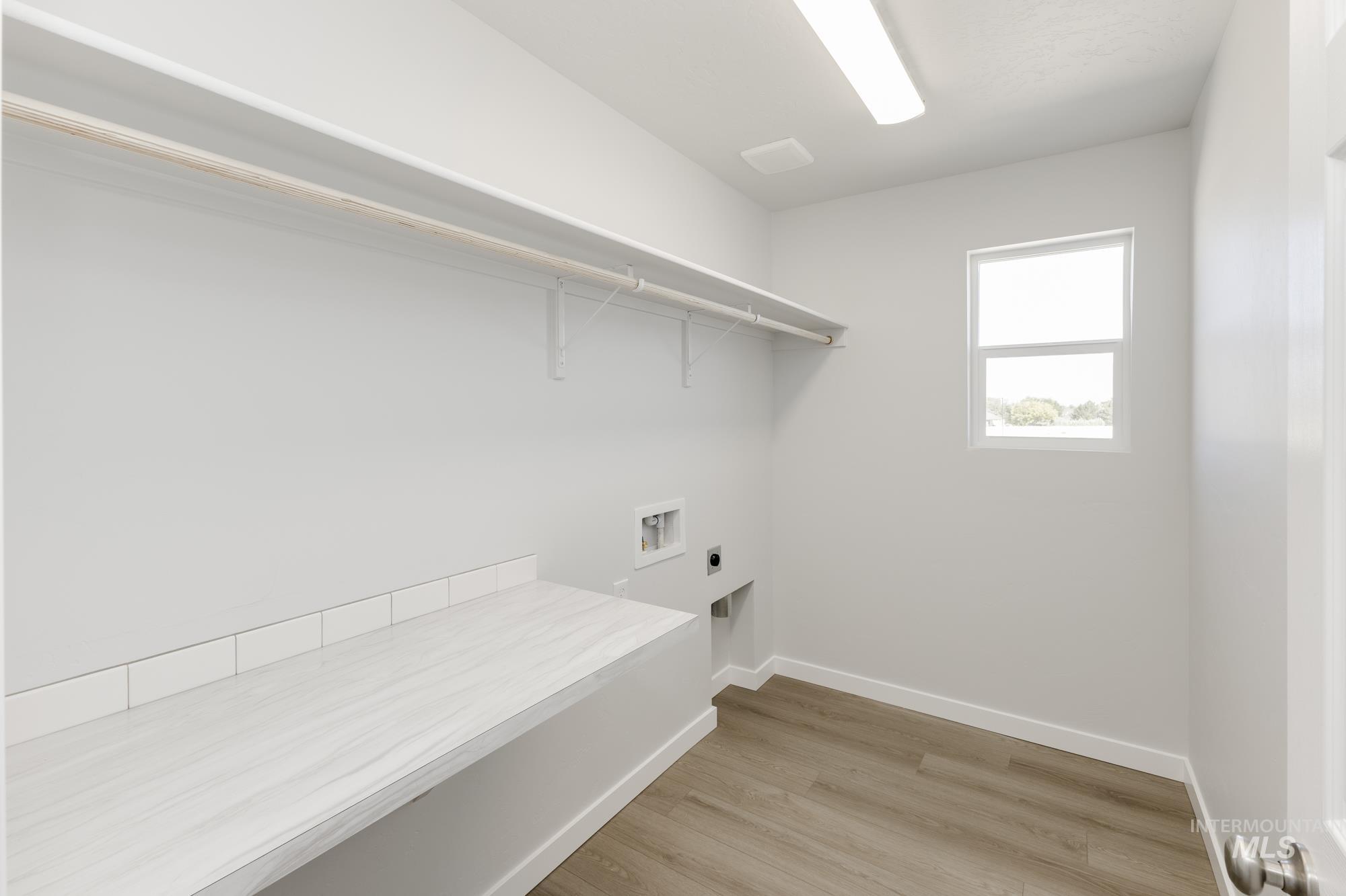 Laundry area with light wood-style flooring, electric dryer hookup, and washer hookup