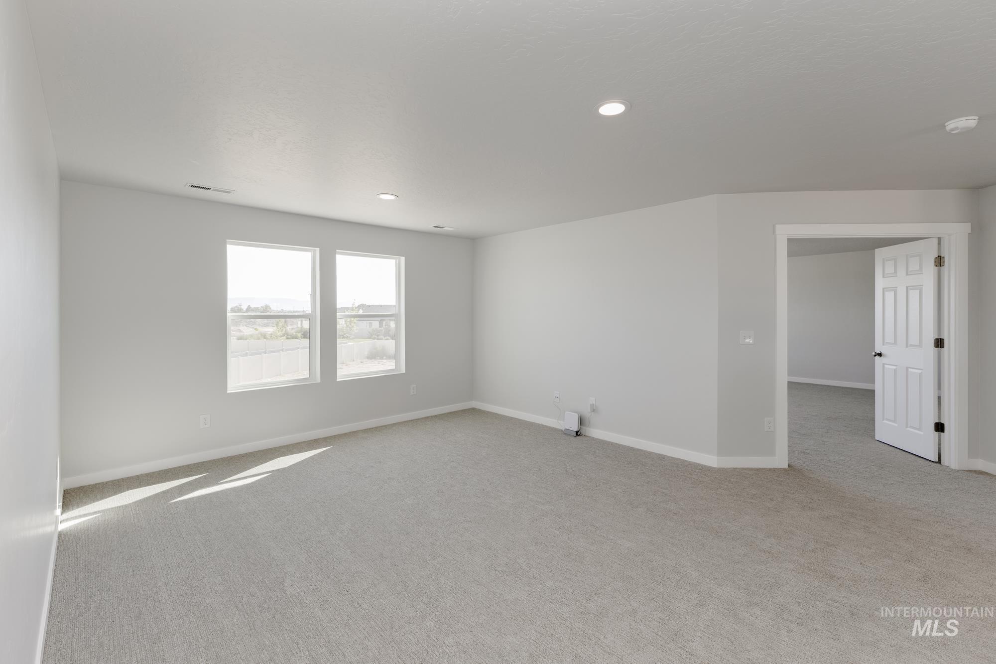 Empty room with light colored carpet and recessed lighting