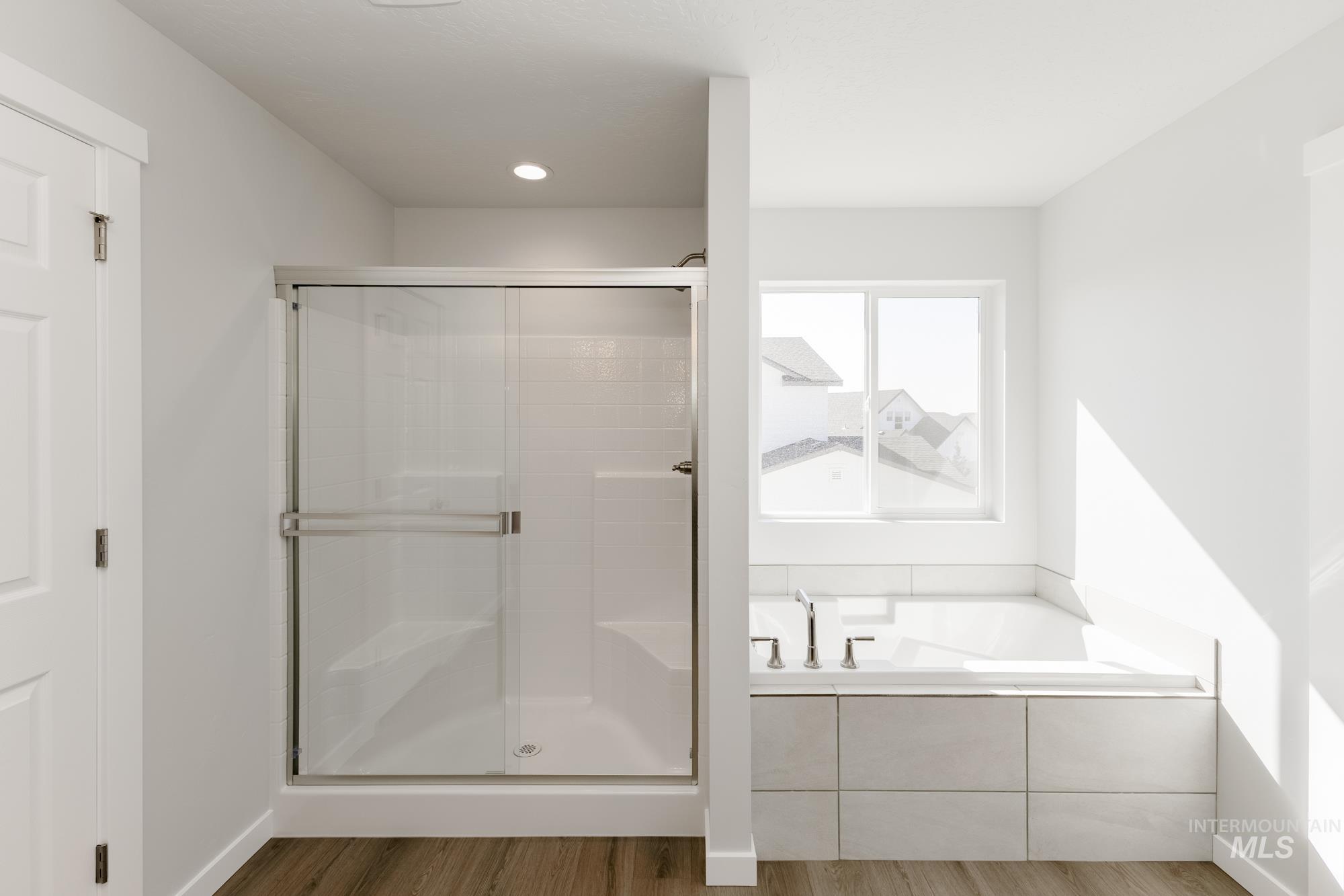 Full bath with a shower stall, a garden tub, wood finished floors, and recessed lighting