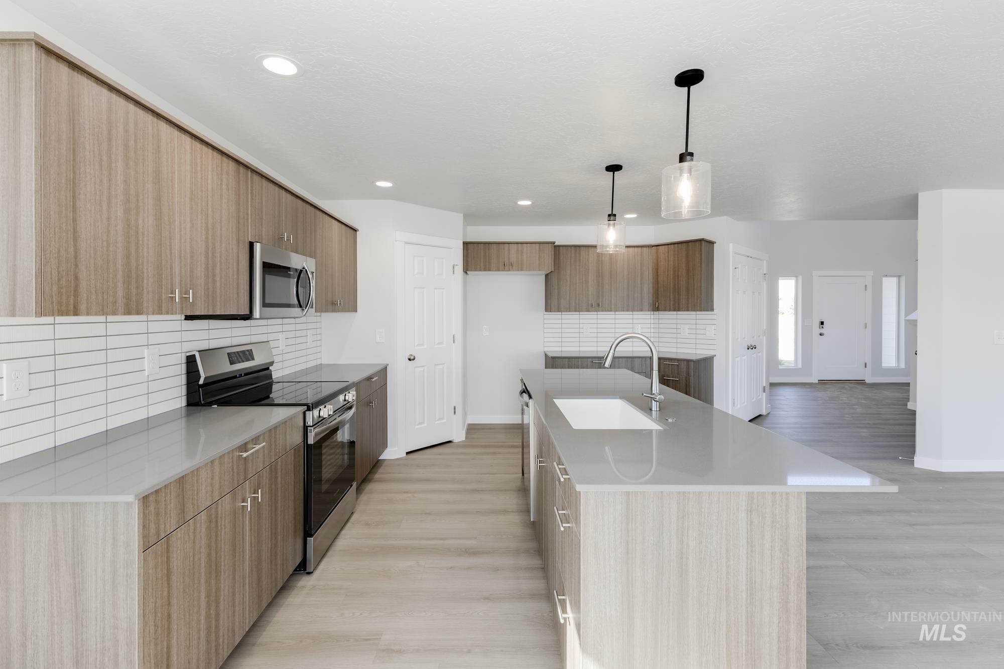 Kitchen with modern cabinets, appliances with stainless steel finishes, tasteful backsplash, light stone counters, and recessed lighting