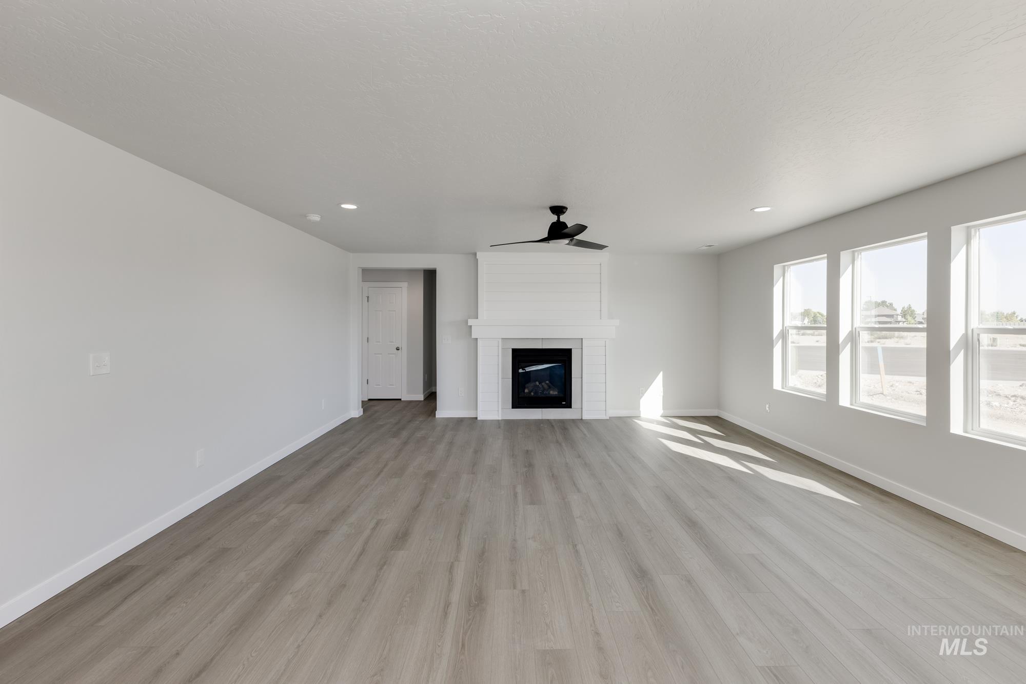 Unfurnished living room with light wood-style floors, a fireplace, ceiling fan, and recessed lighting