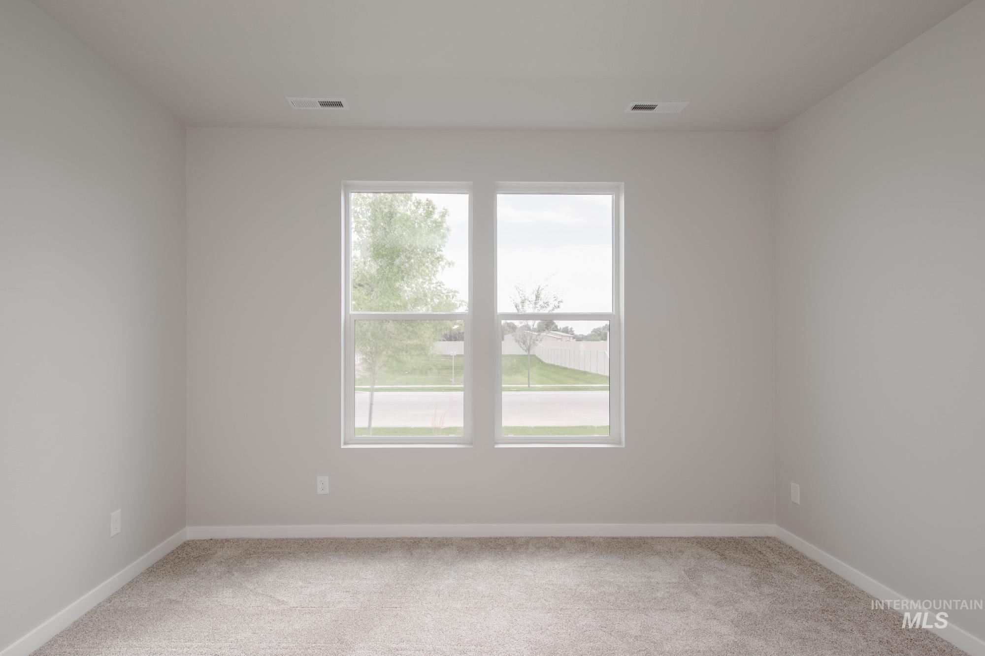 Empty room featuring light colored carpet and baseboards