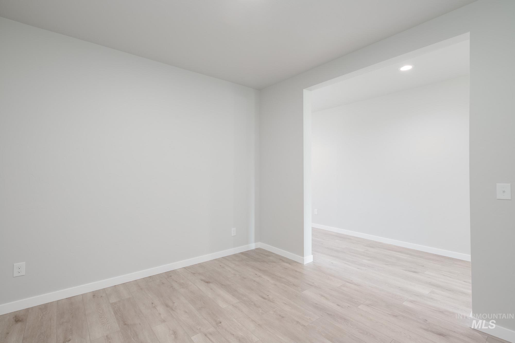 Empty room with light wood finished floors and recessed lighting