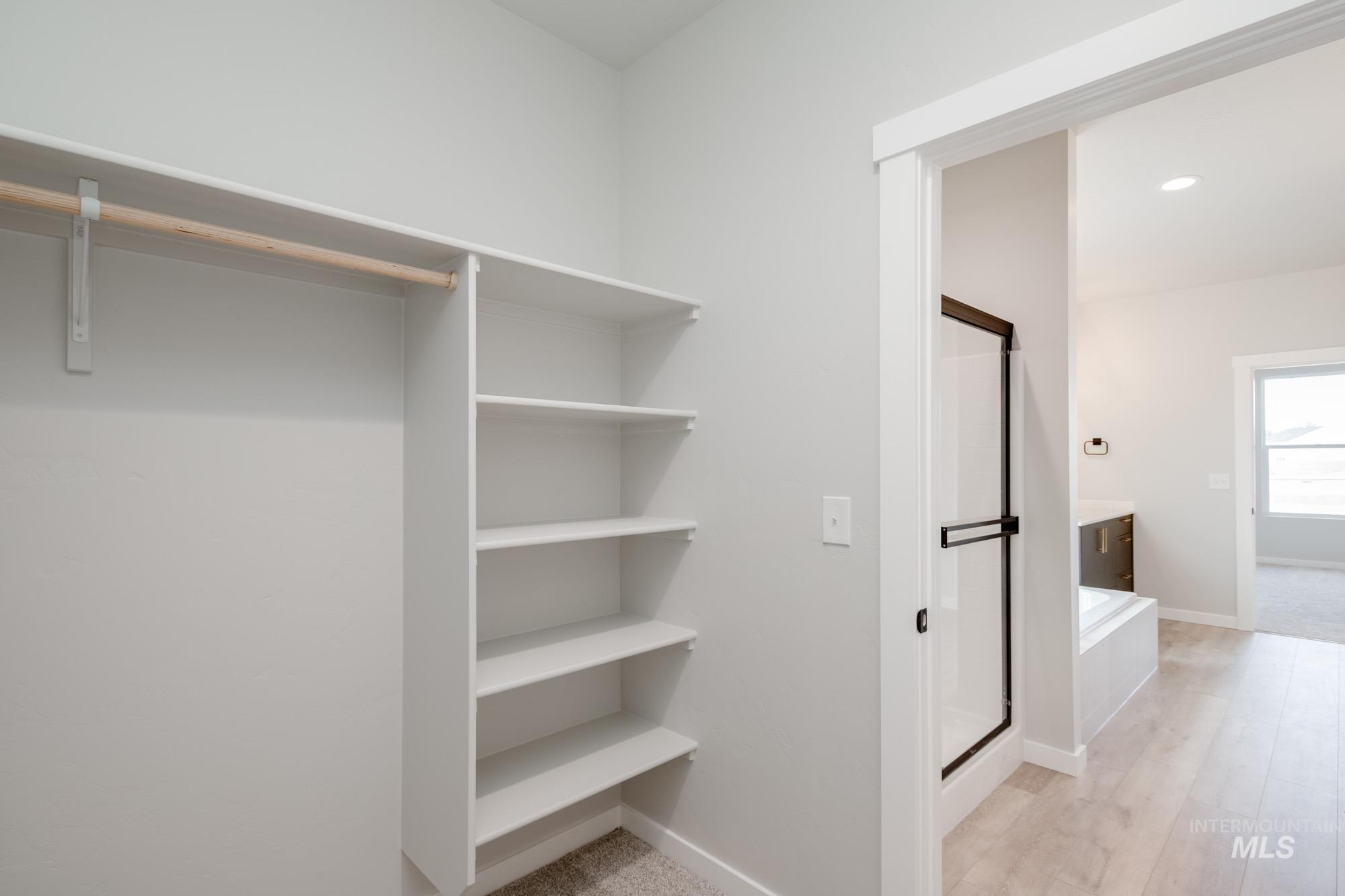 Walk in closet with light wood finished floors