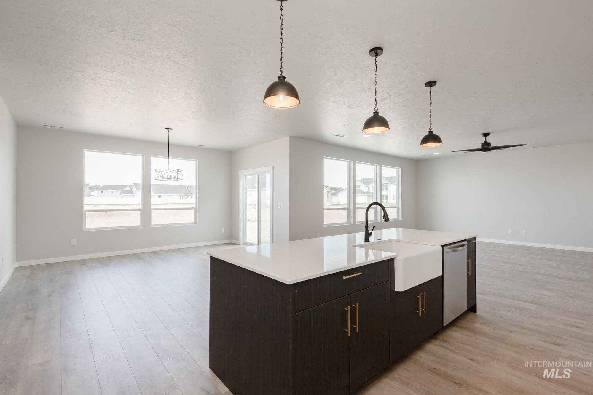 Kitchen with open floor plan, decorative light fixtures, a ceiling fan, light wood-type flooring, and a textured ceiling