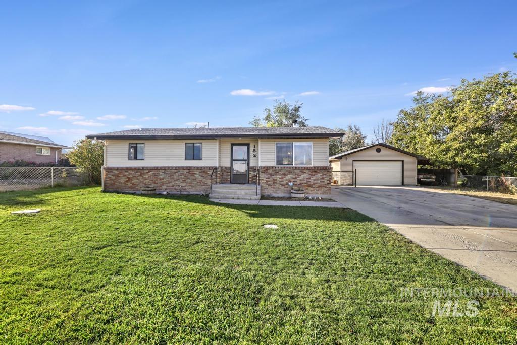 Single story home featuring brick siding, a detached garage, an outdoor structure, and driveway