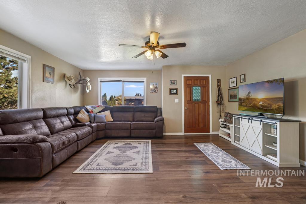 Living area with a textured ceiling, a ceiling fan, and dark wood-style flooring